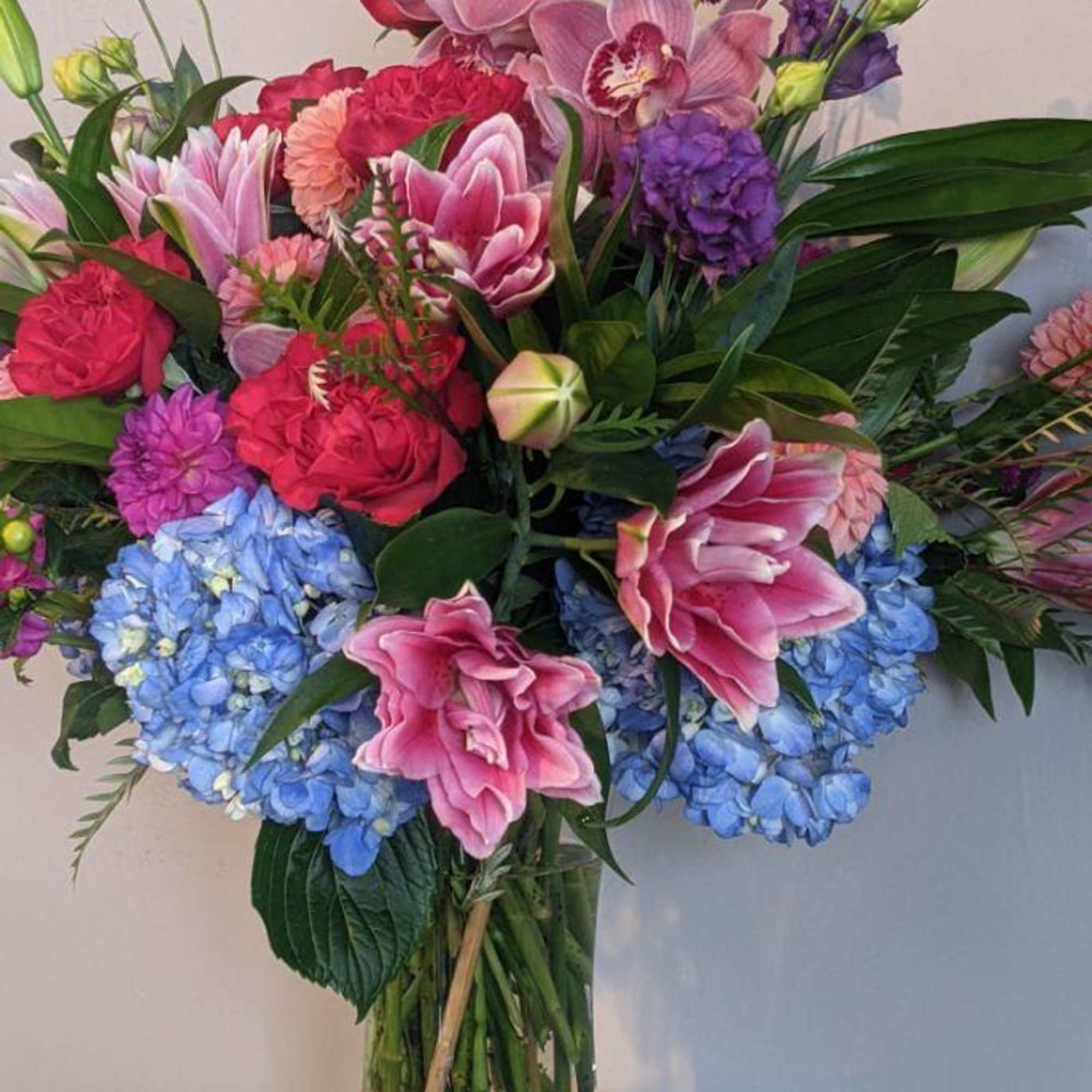 Mixed pink and blue floral arrangement in a clear glass vase