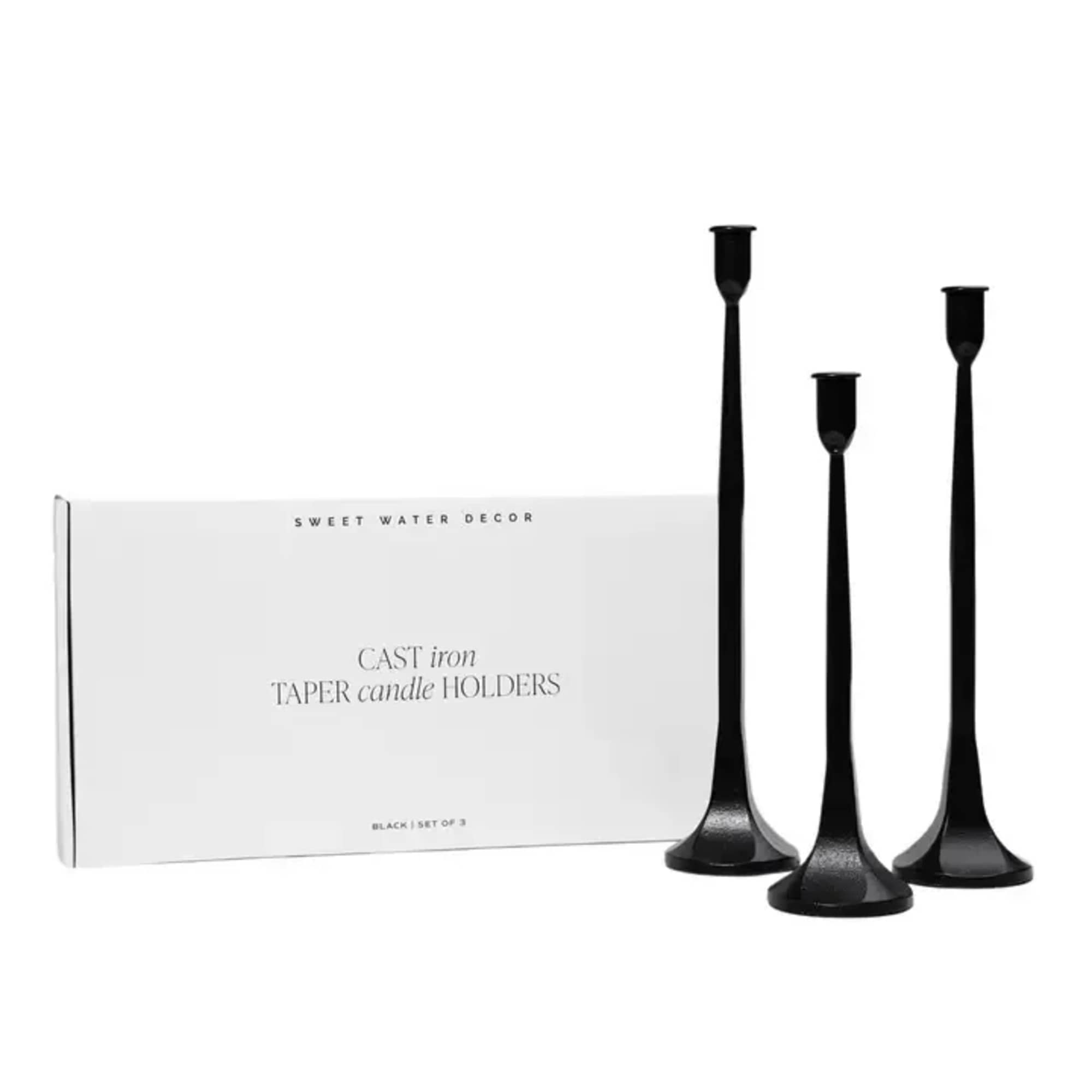 Set of three black taper candle holders beside a product box