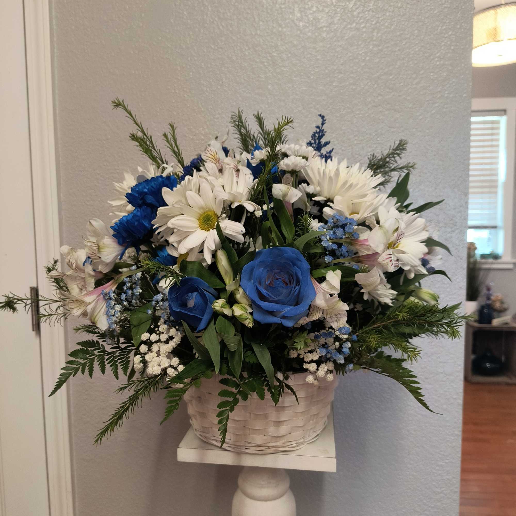 Blue and white flower arrangement in a white basket