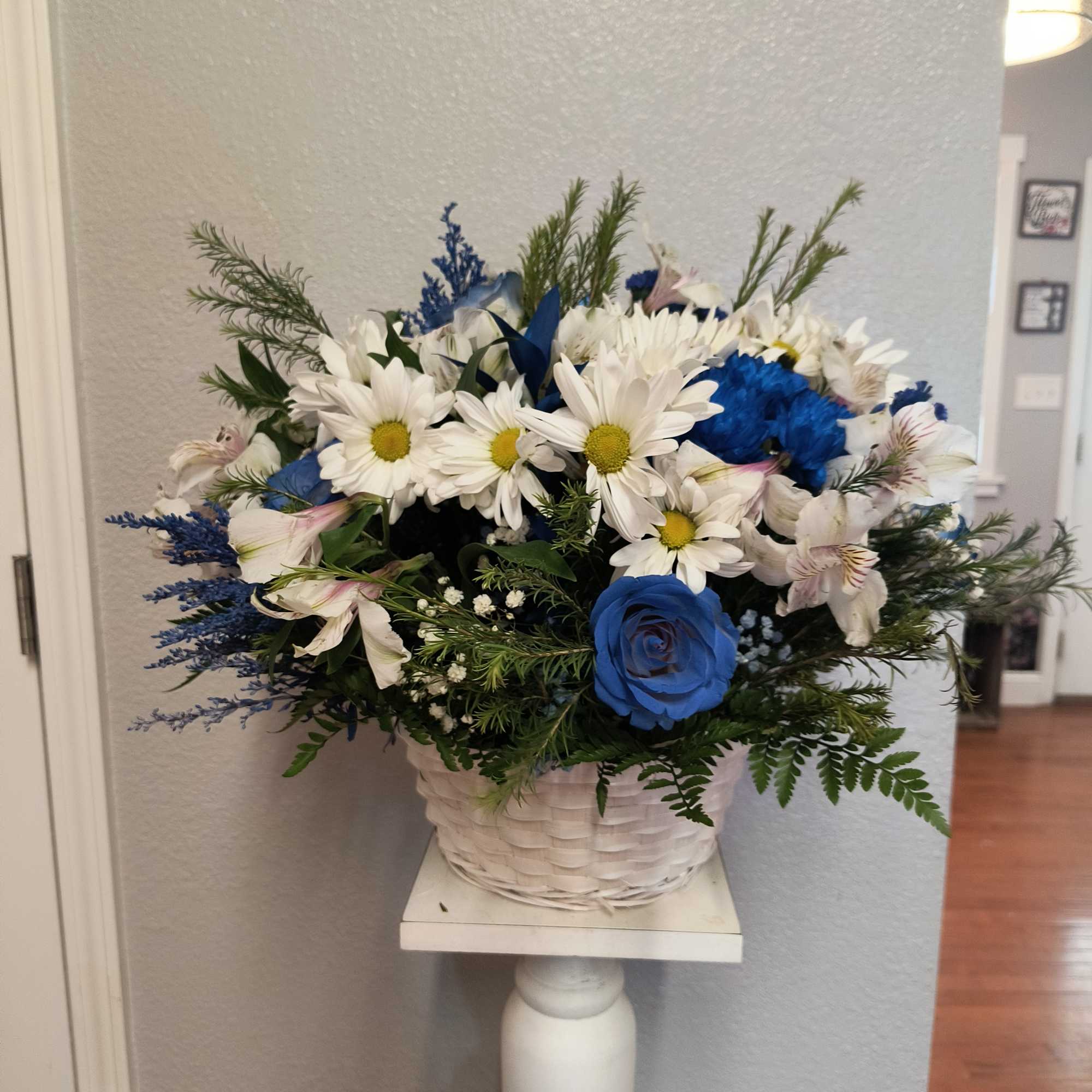 Blue and white flower arrangement in a white basket on a pedestal