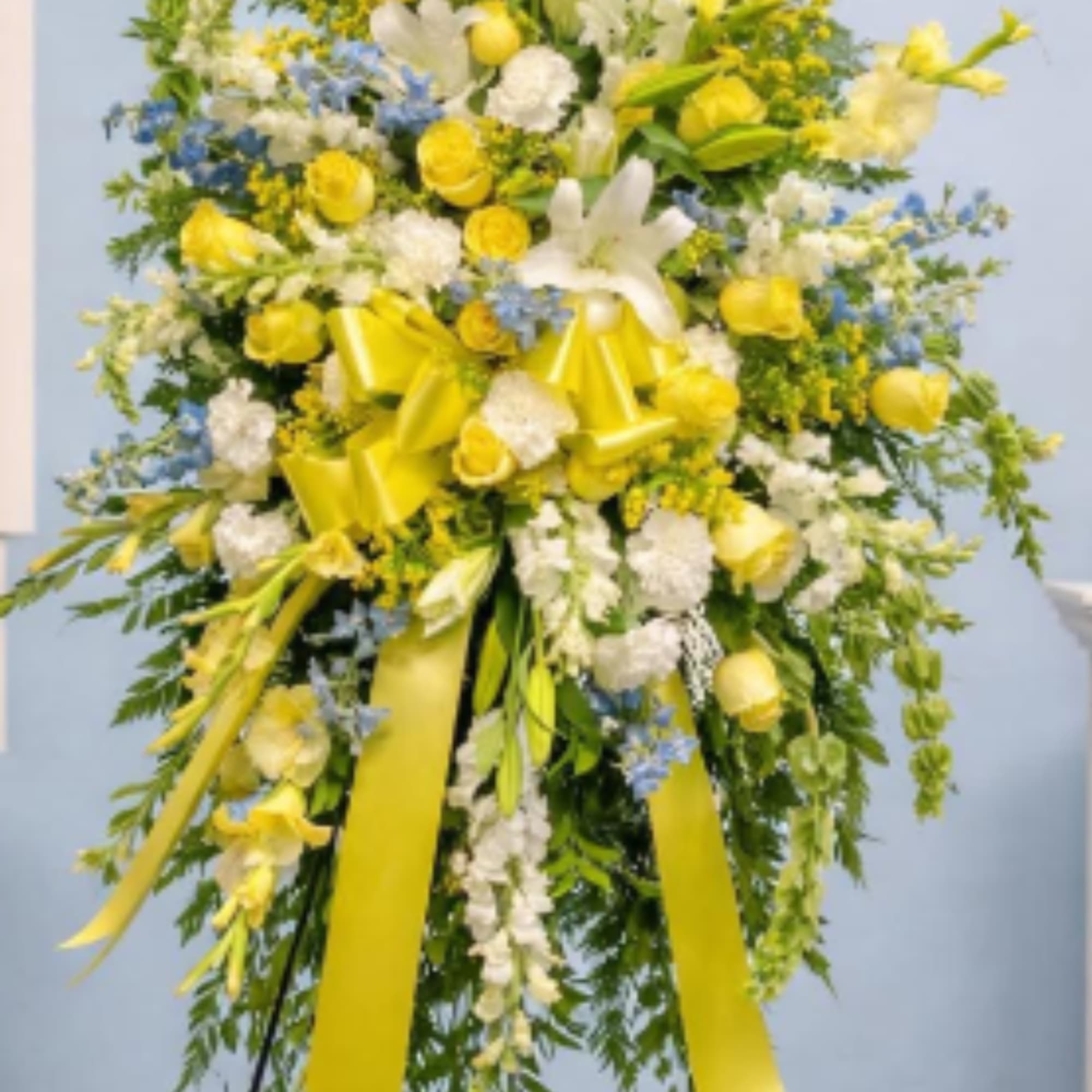 A yellow and white standing spray for a grand, traditional sympathy display