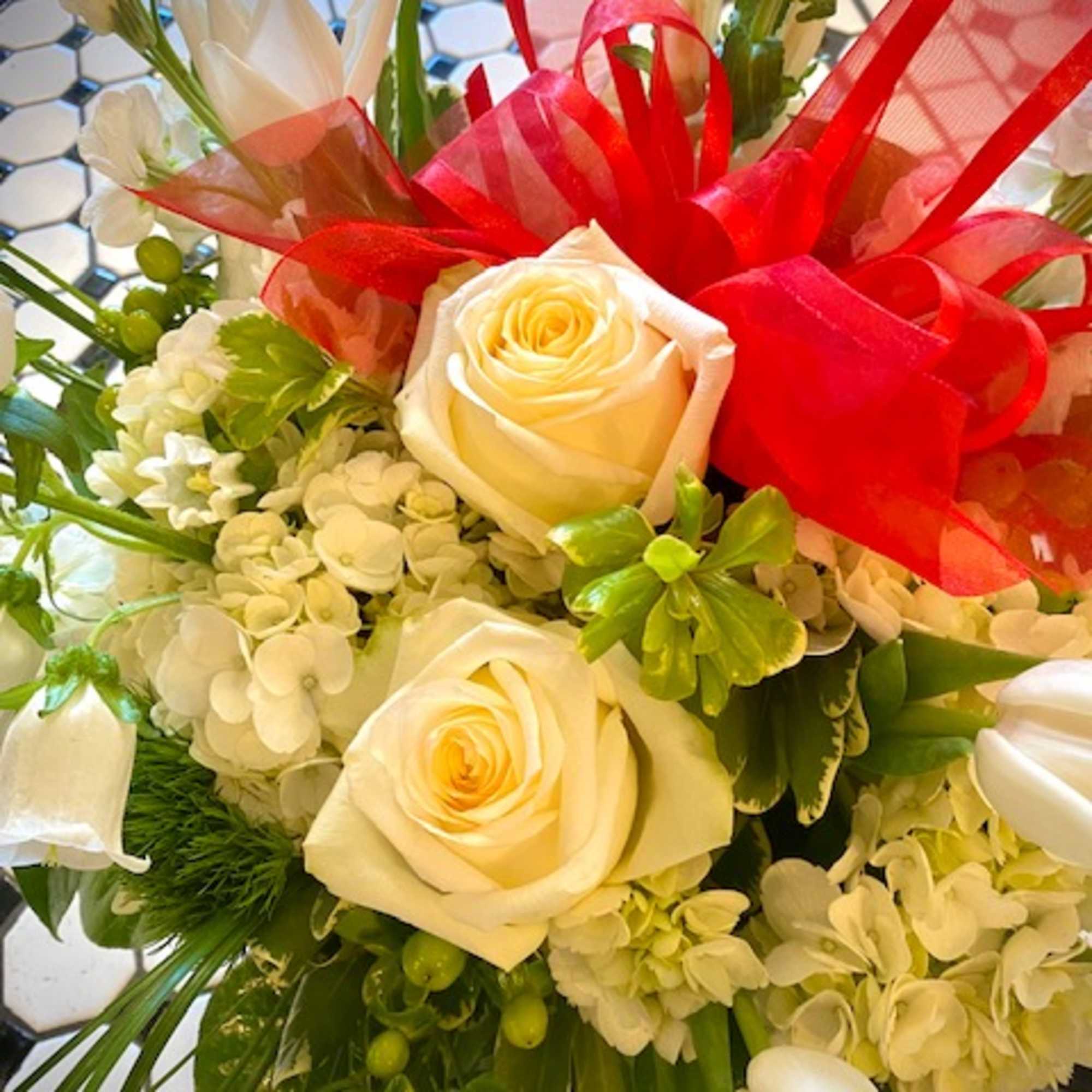 Bouquet of cream roses and white flowers tied with a bright red ribbon
