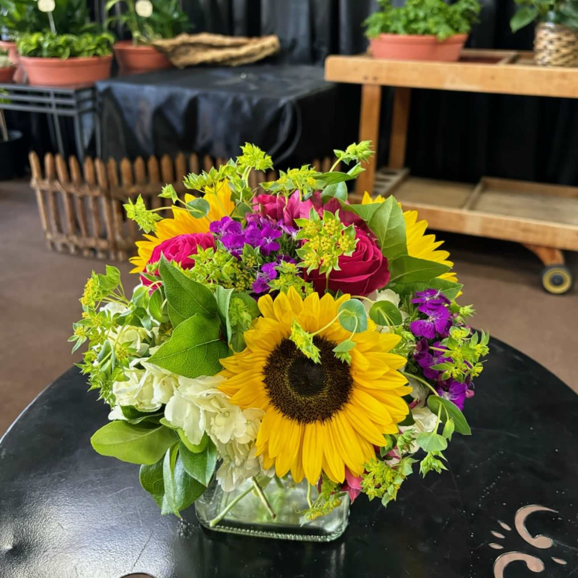Bouquet of sunflowers, pink roses, and white hydrangeas in a glass vase