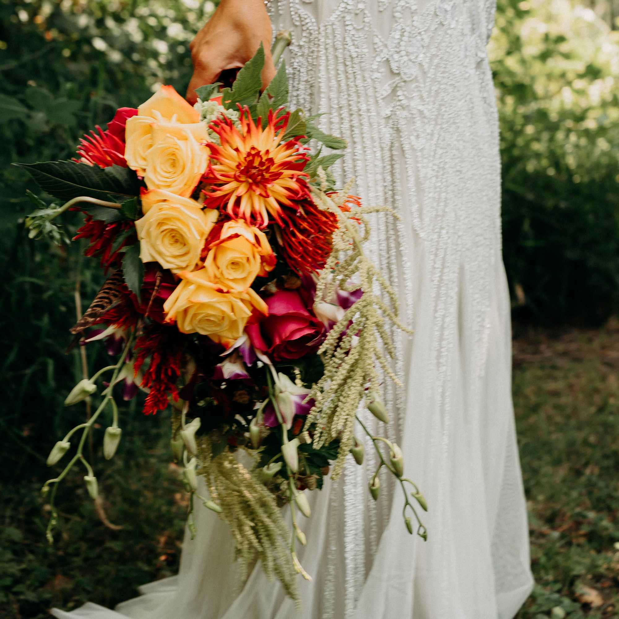 Bride holding a cascading bouquet of roses and orange-red blooms
