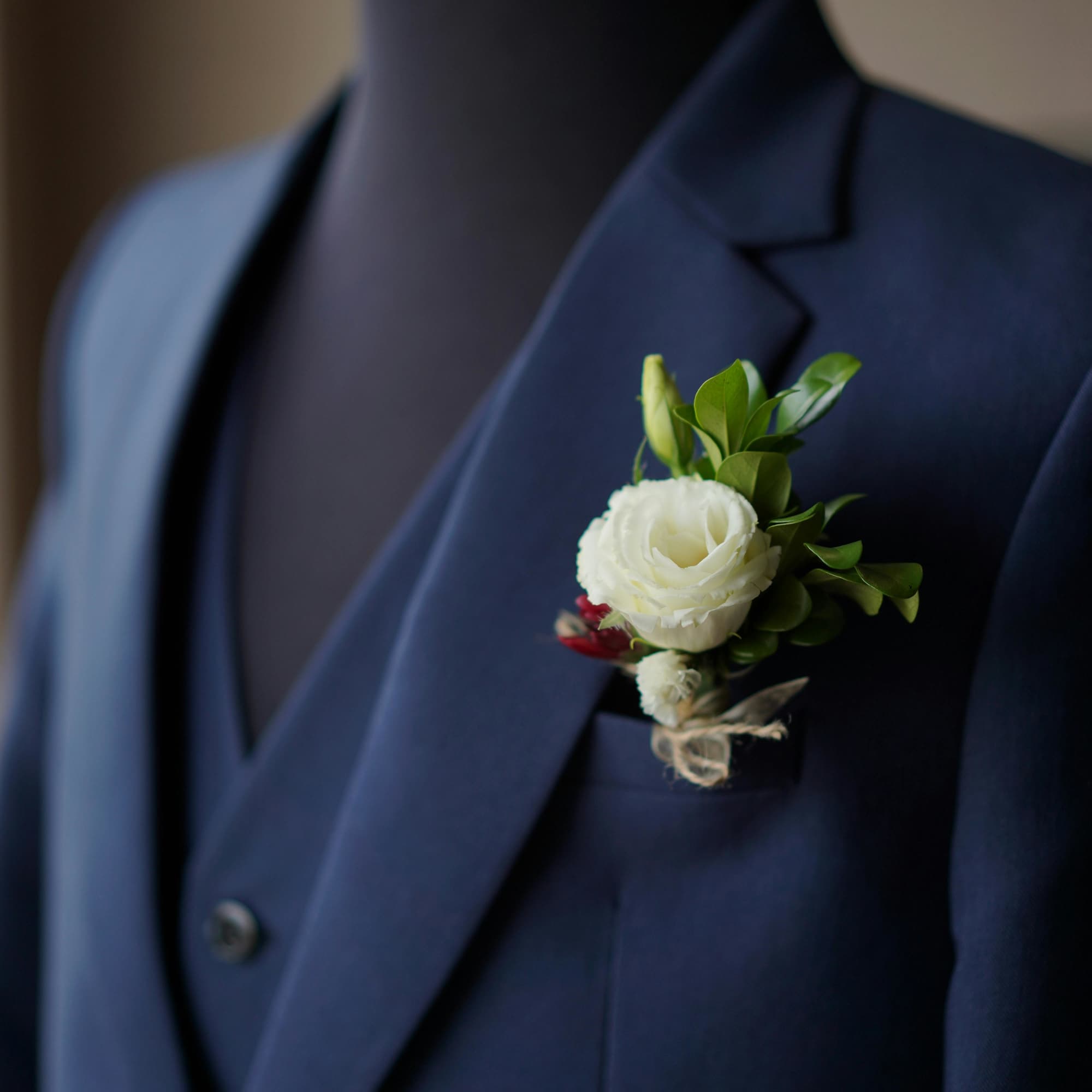 White boutonniere pinned to a navy suit jacket
