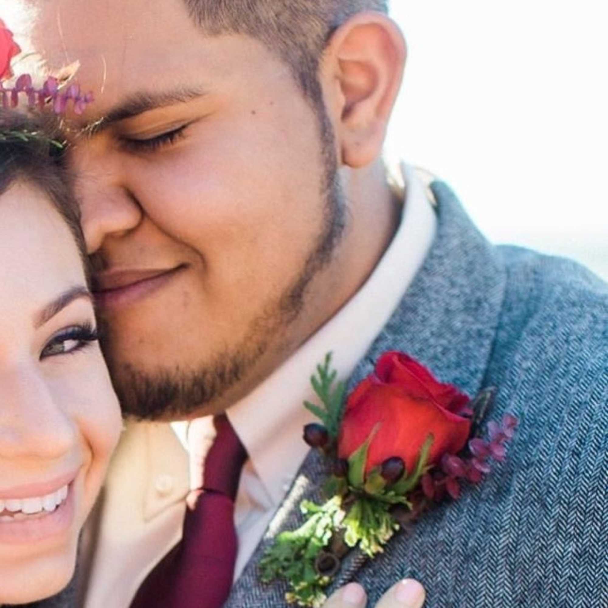 Couple embracing, with a red rose boutonniere on the man's jacket