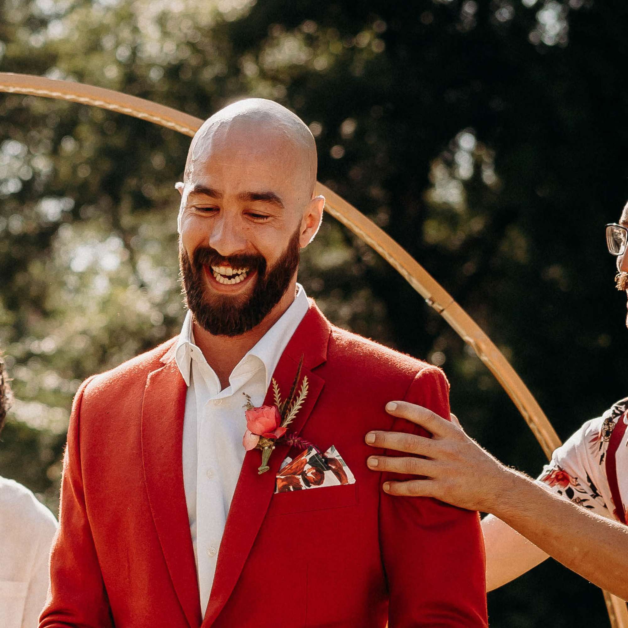 Man in a red suit wearing a pink boutonniere