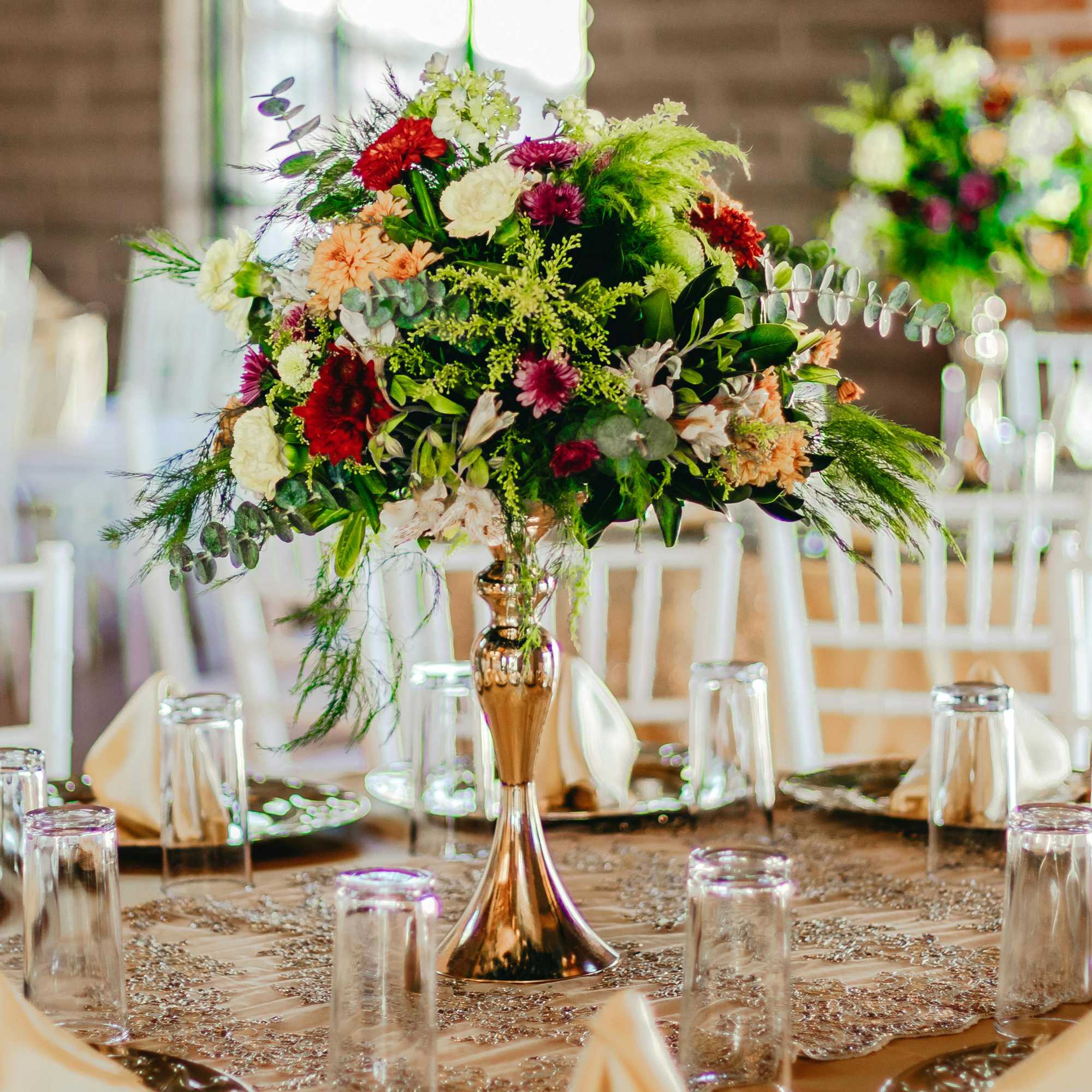 Large mixed floral centerpiece in a gold vase on a decorated table