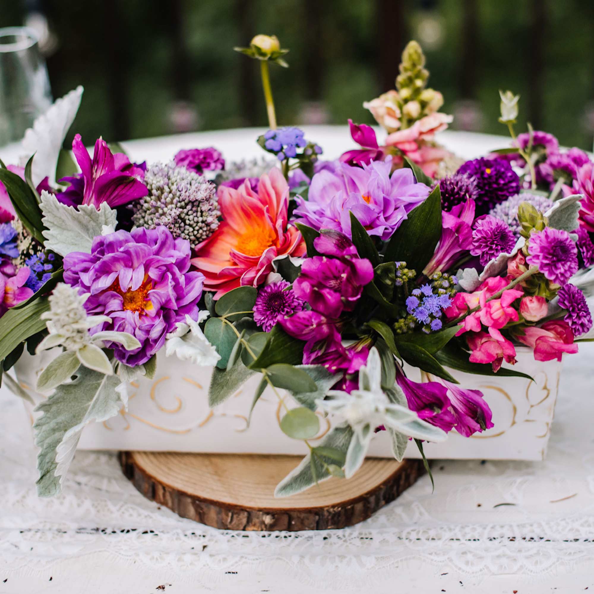 Colorful floral centerpiece in a white rectangular container on a table