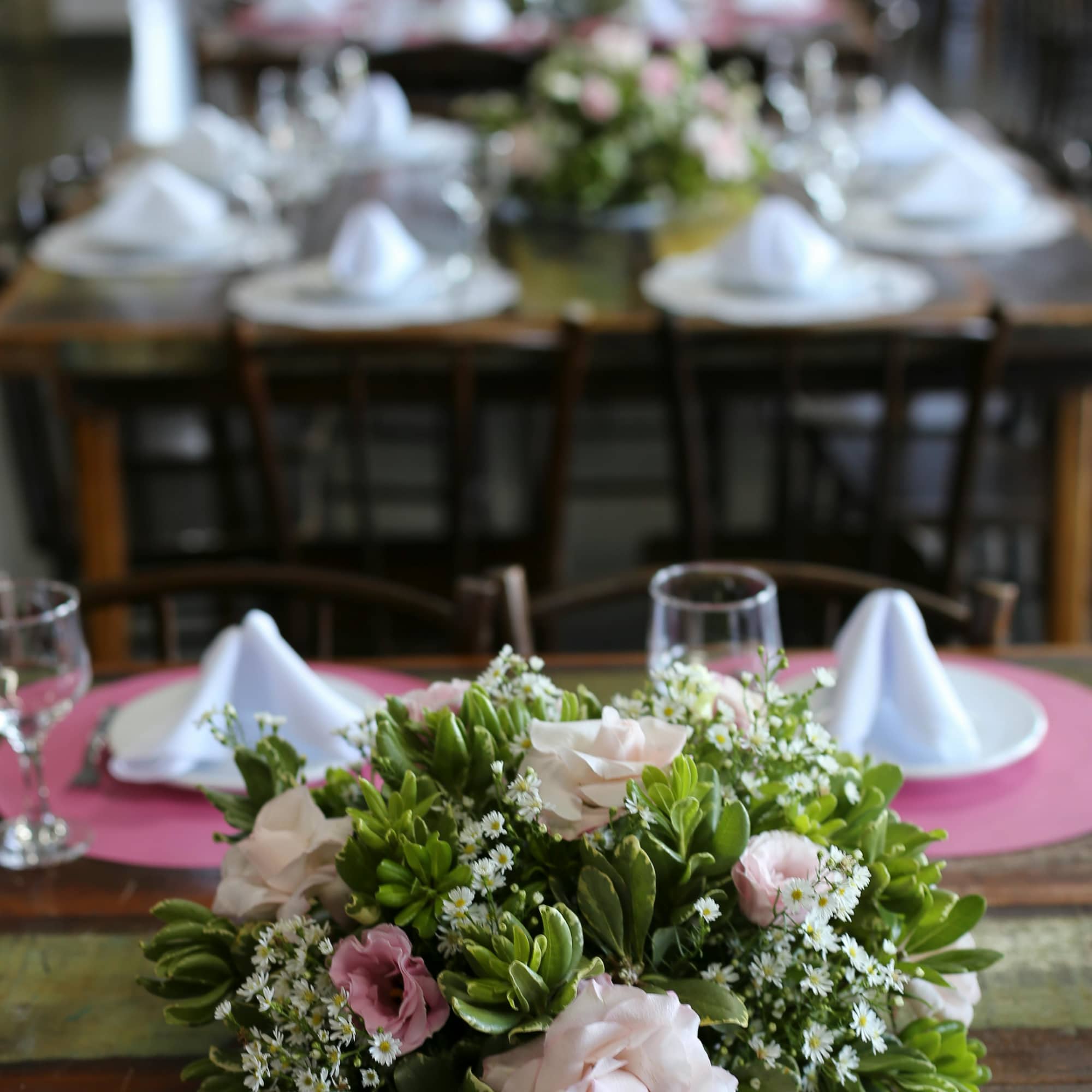 Low floral centerpiece with pale pink roses and white daisies on a table
