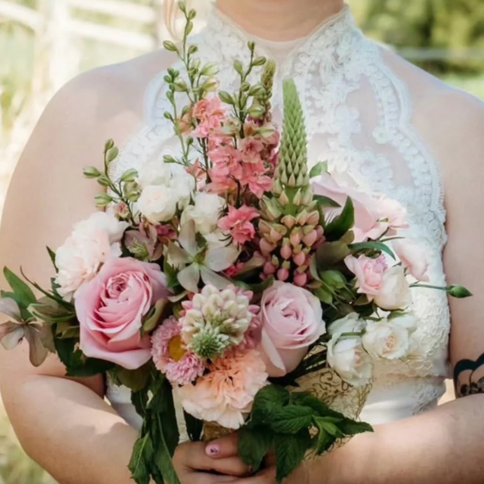 Bride holding a pink and white bouquet with roses and mixed blooms