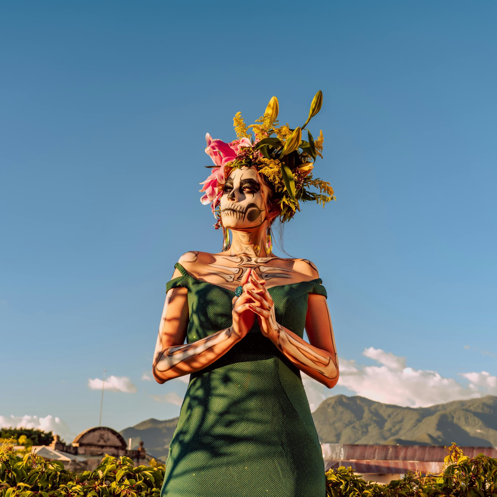 Woman in a green dress with a floral crown and face paint outdoors