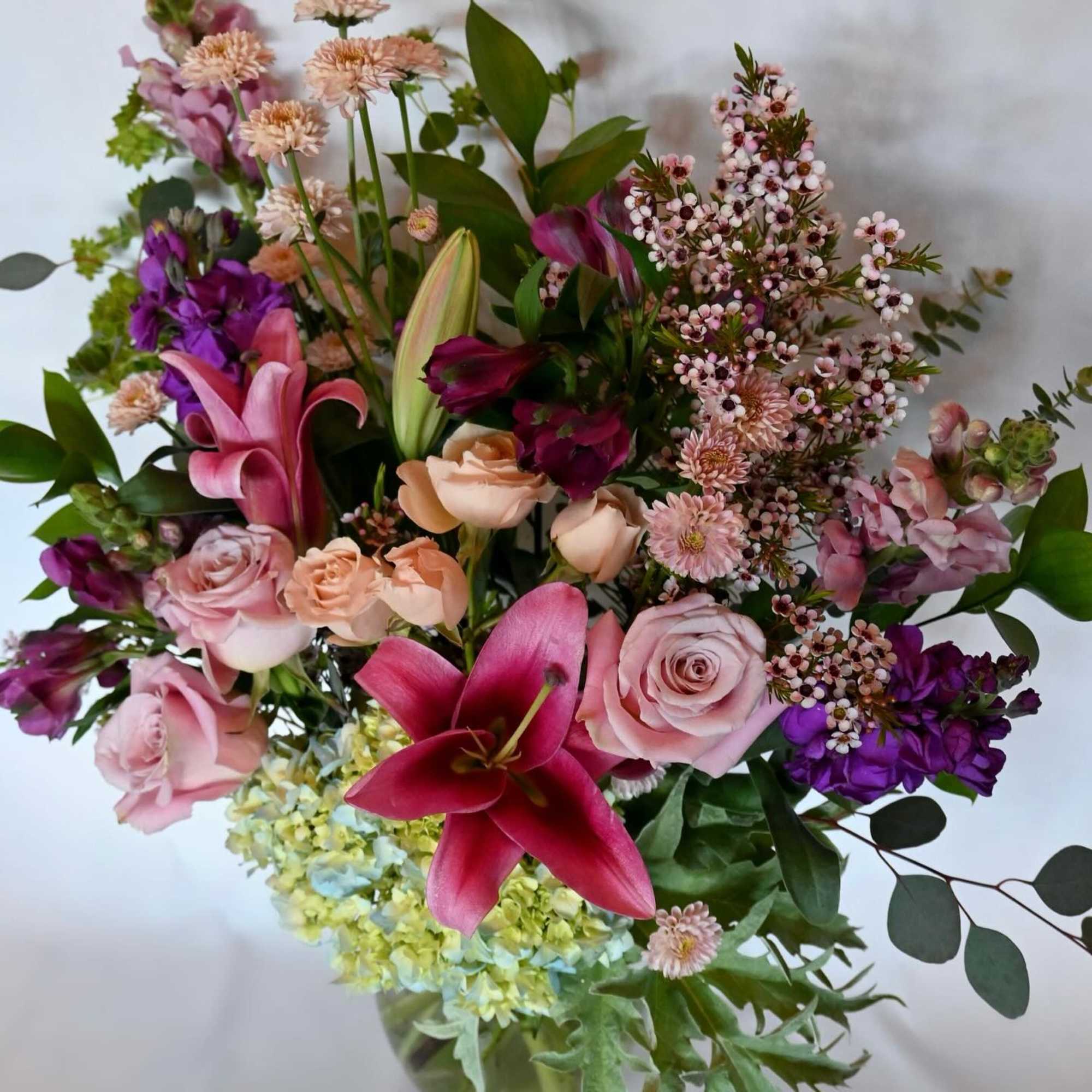 Mixed bouquet of pink, purple, and peach flowers in a glass vase