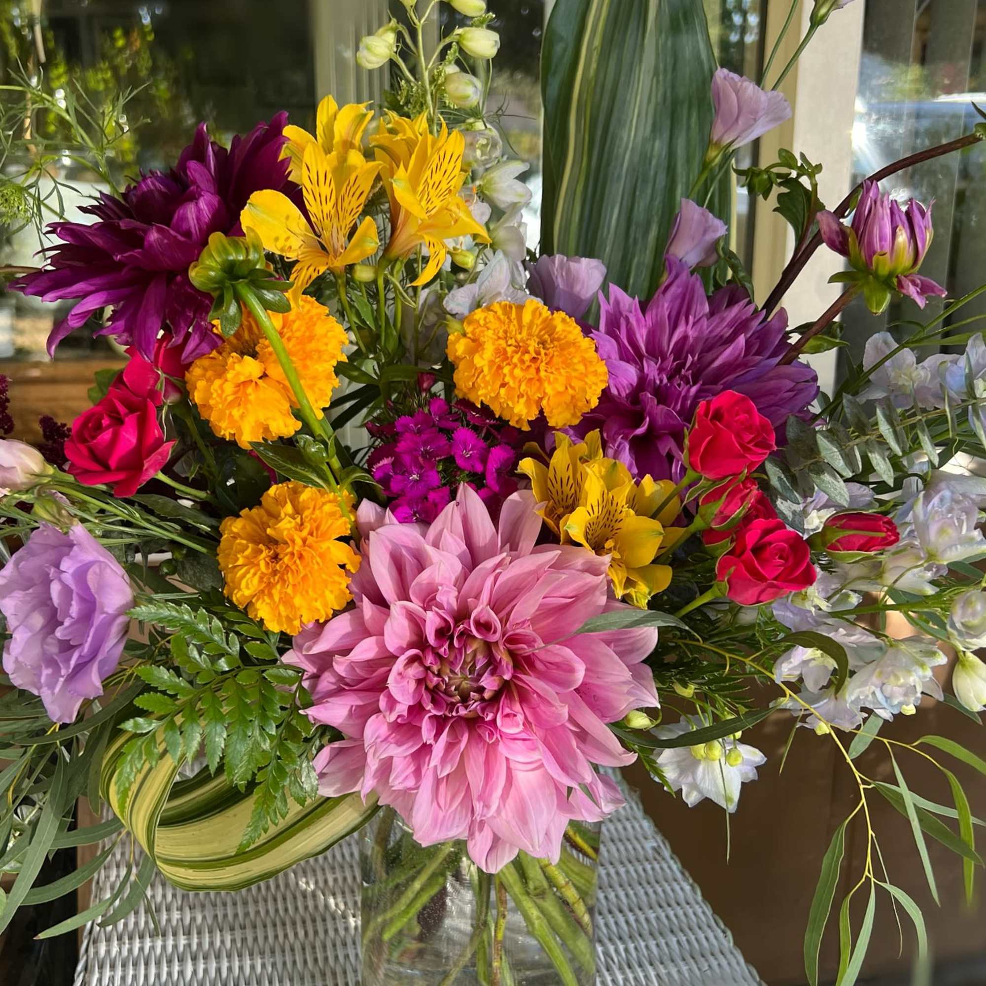 Mixed bouquet of pink, purple, and yellow flowers in a glass vase