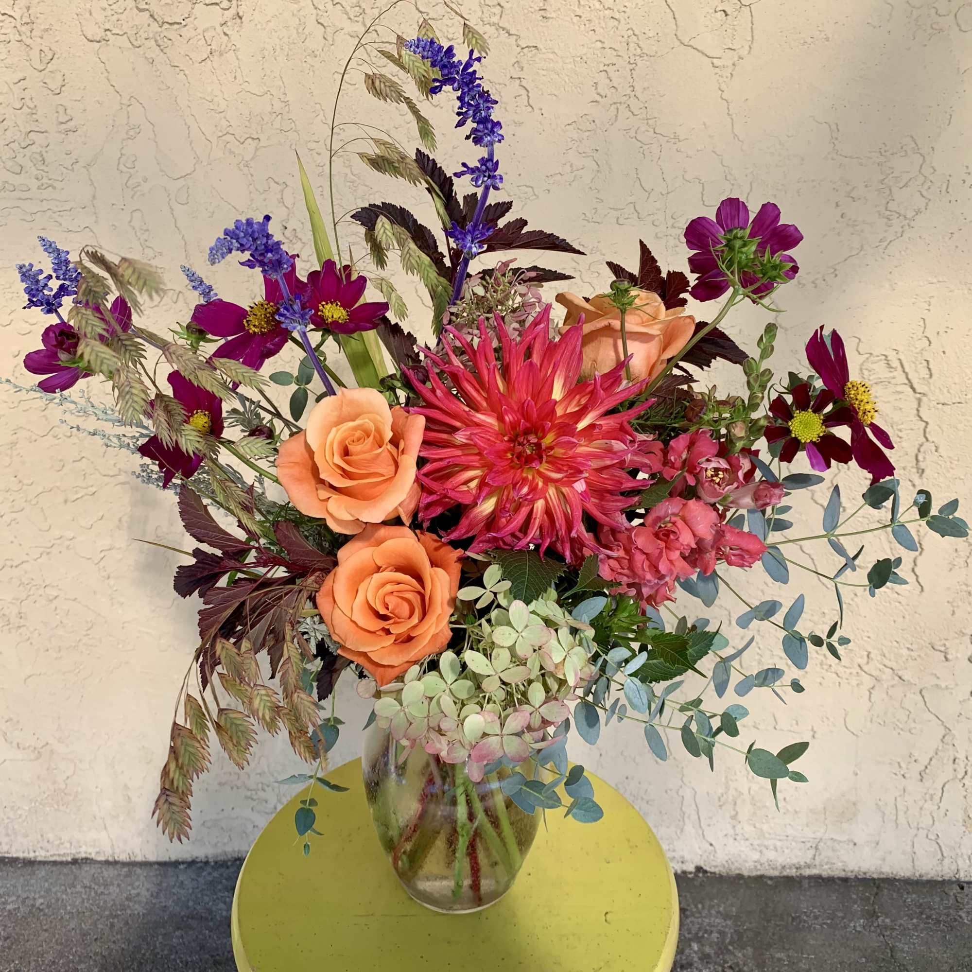 Mixed bouquet in a glass vase with orange roses and a pink dahlia