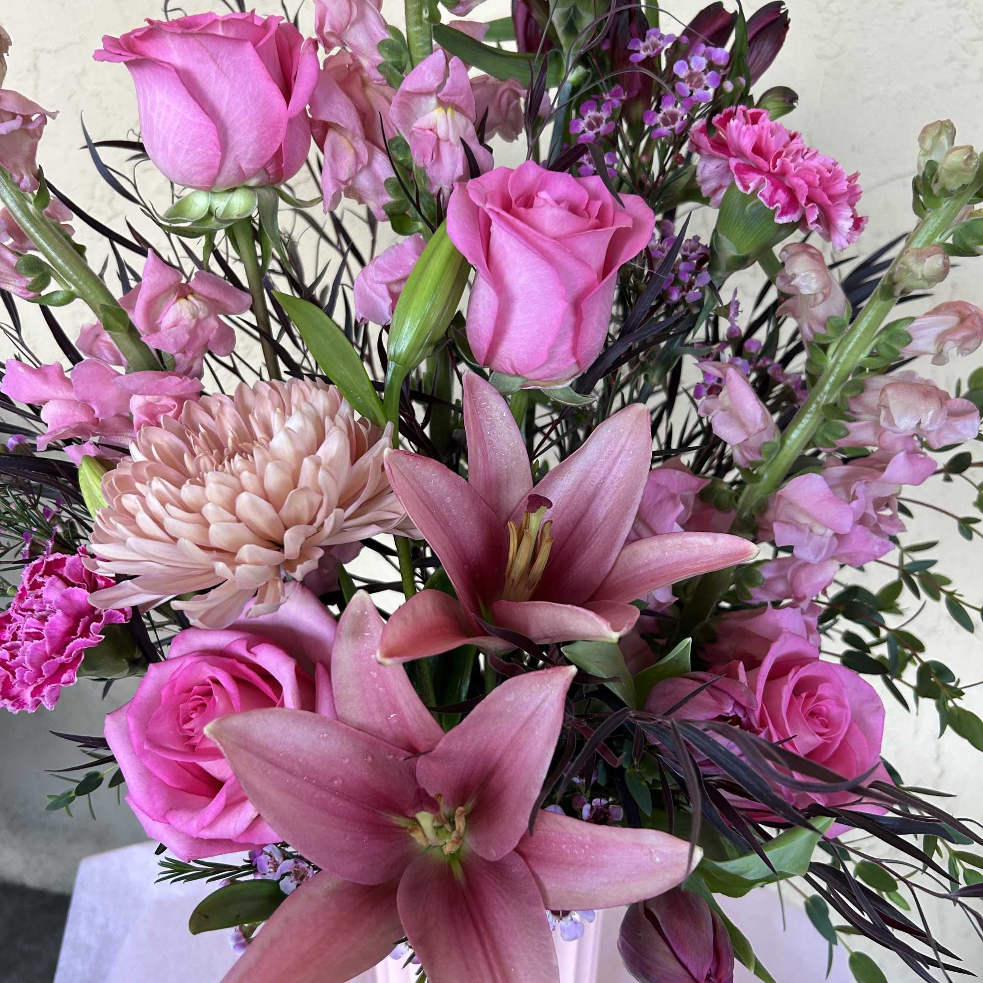 Pink roses and lilies arranged in a white vase
