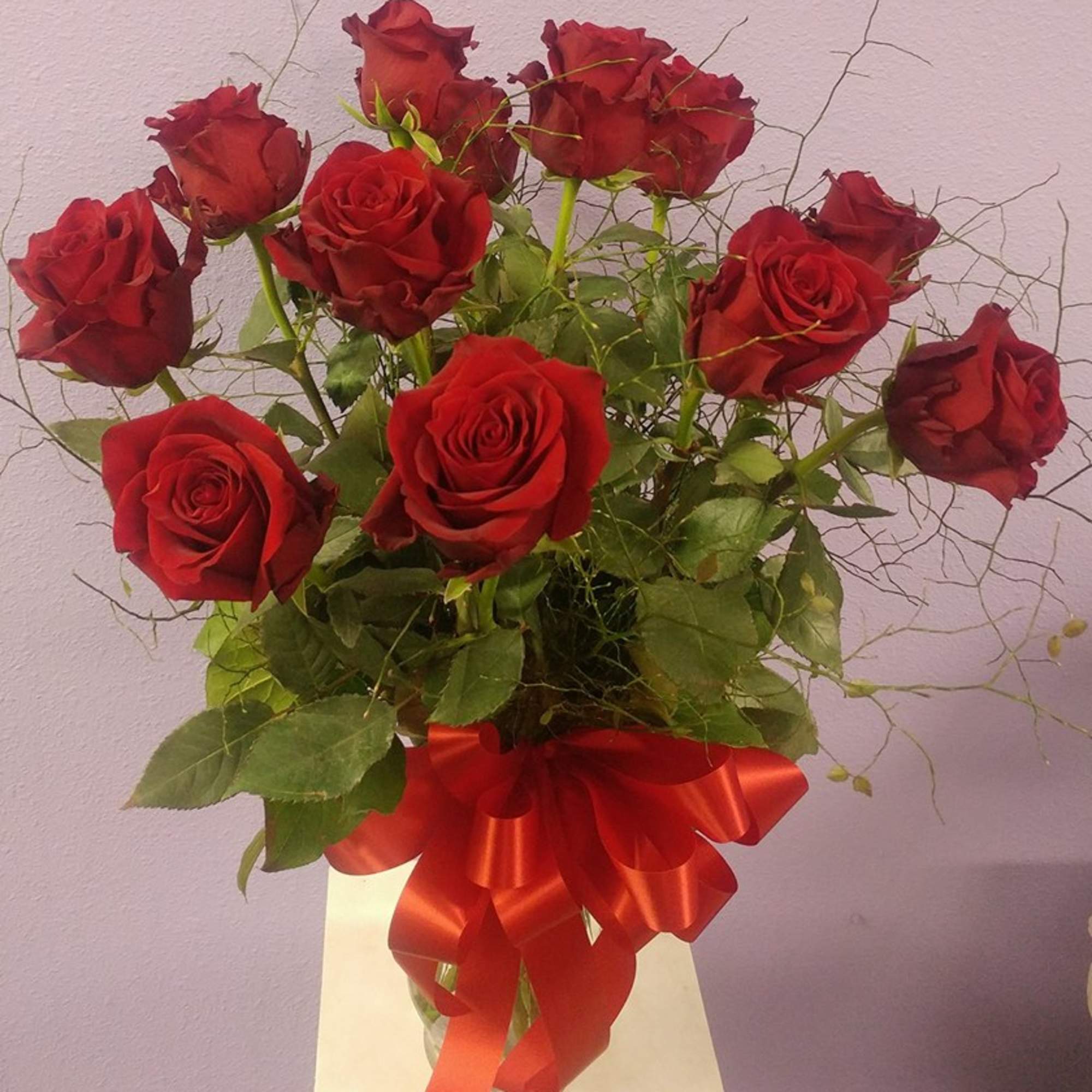 Bouquet of red roses in a glass vase with a red ribbon