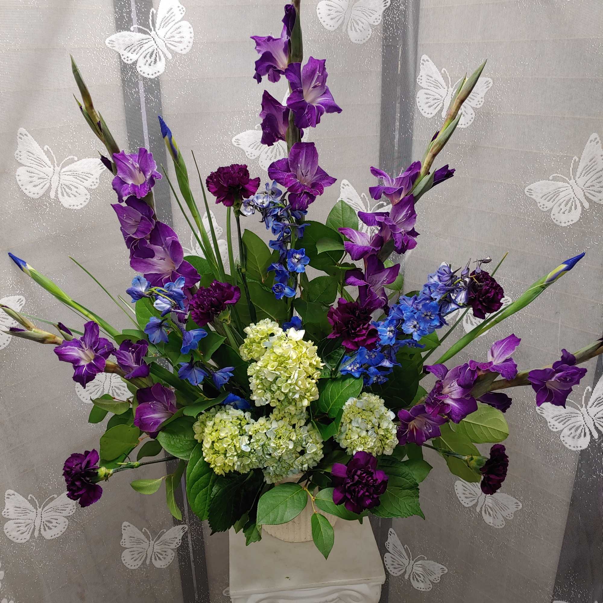 Tall purple and blue floral arrangement in a vase