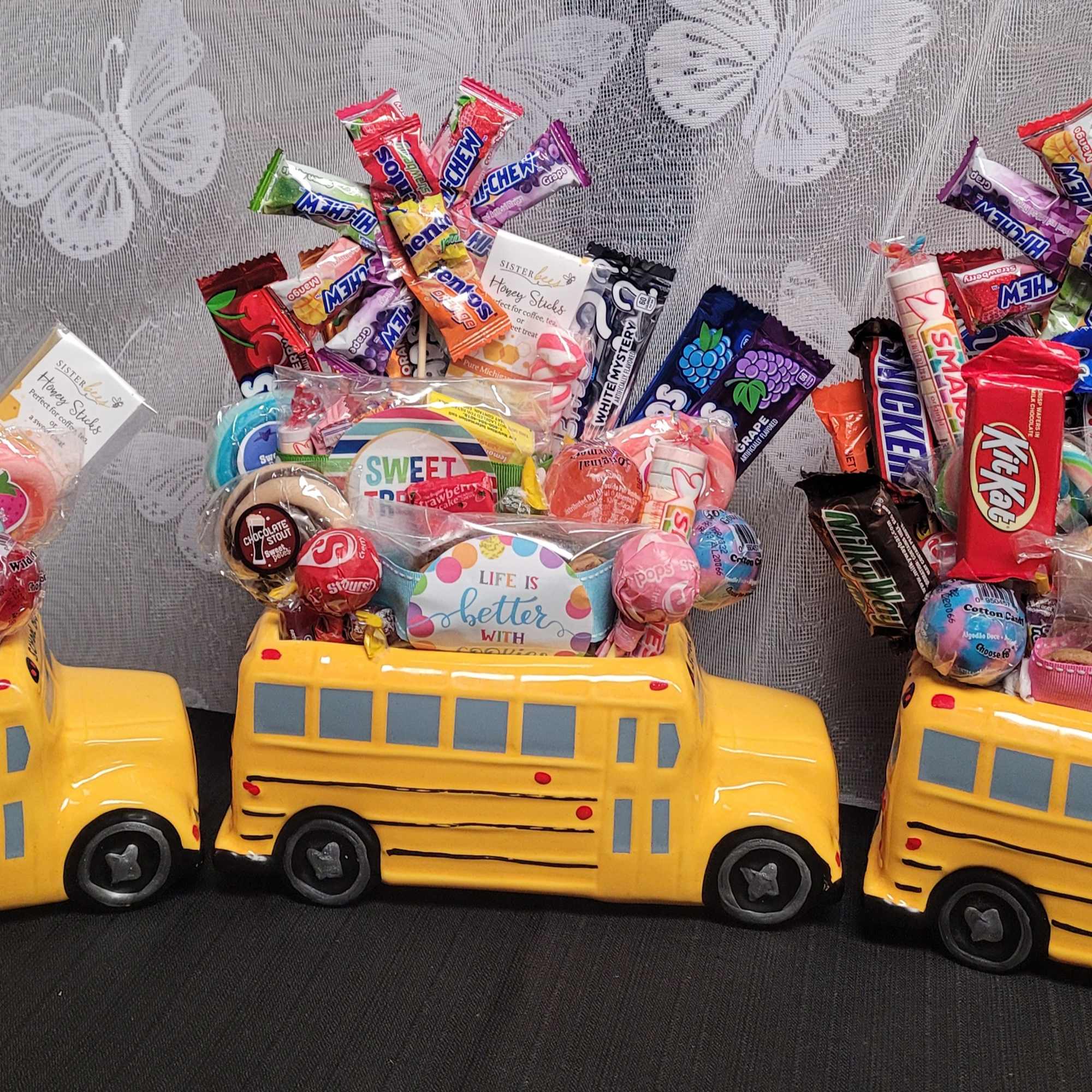 Three yellow school bus candy containers filled with assorted sweets