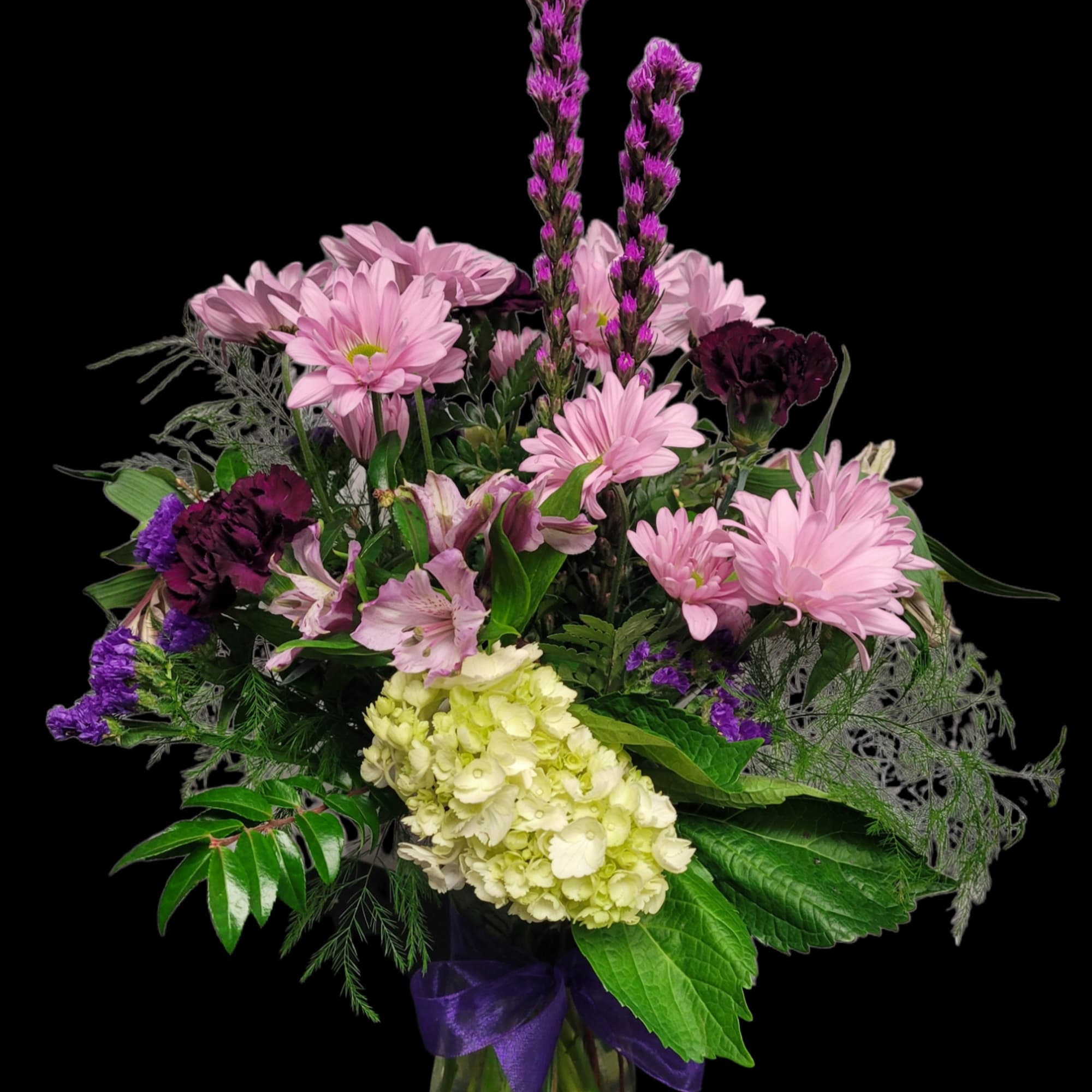Pink and purple mixed bouquet in a glass vase with a purple ribbon