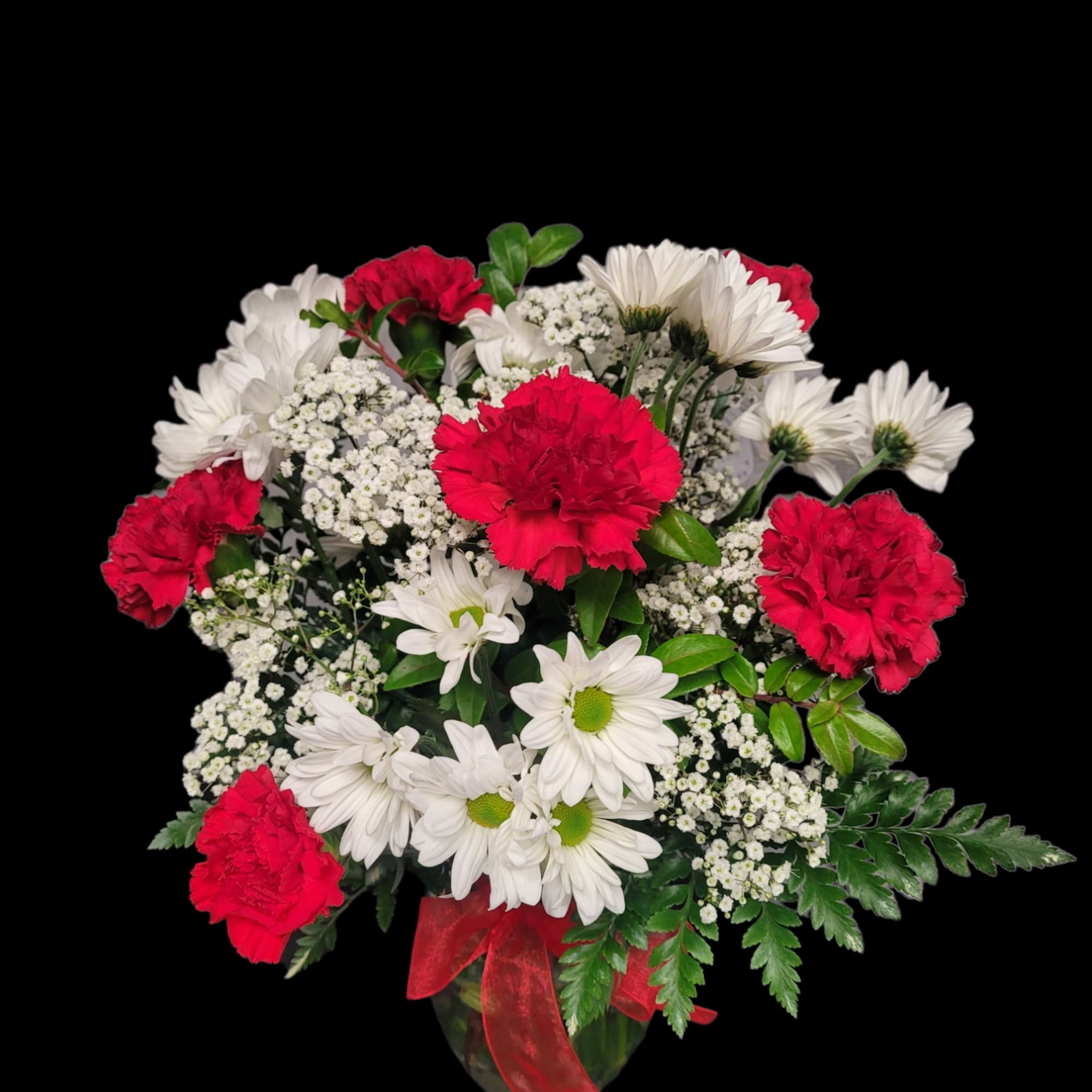 Red carnations and white daisies in a glass vase with a red ribbon