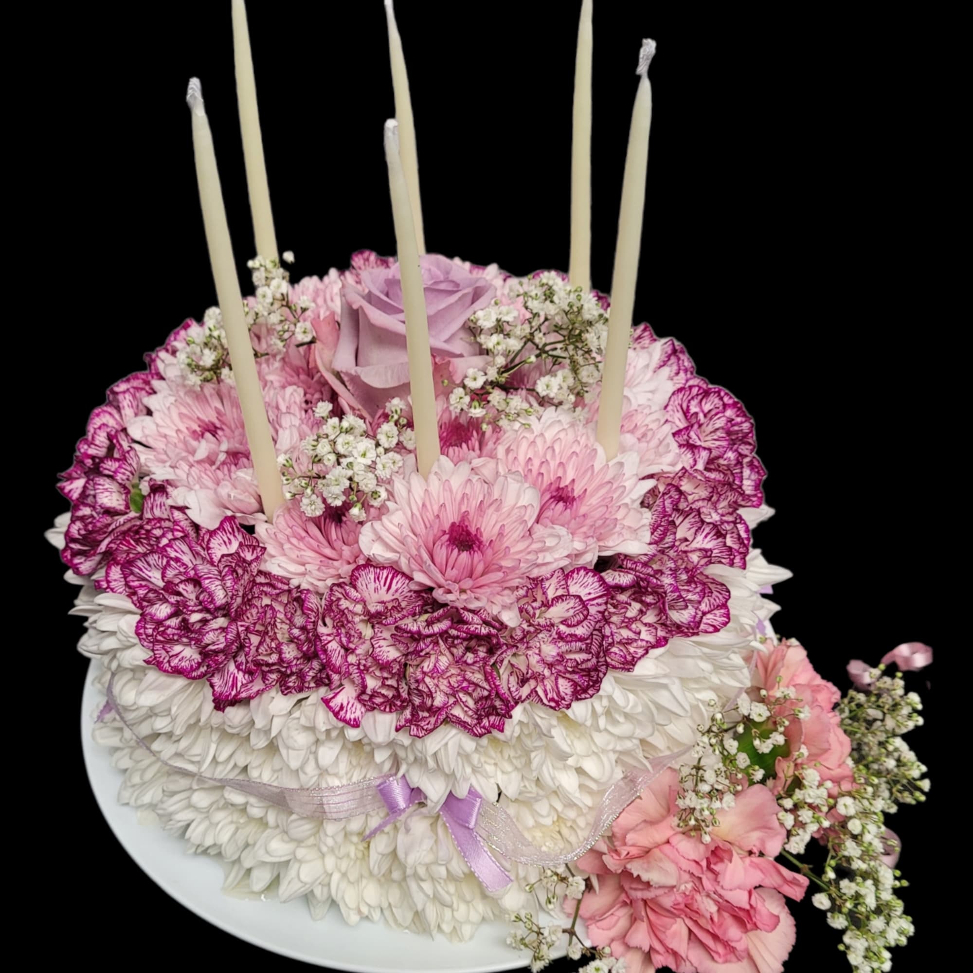 Pink and white floral cake with candles on a plate