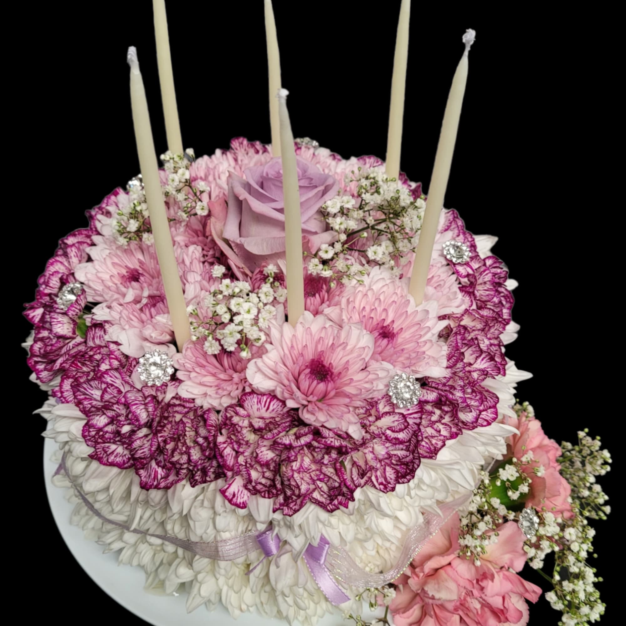Pink and white floral cake with candles on a plate