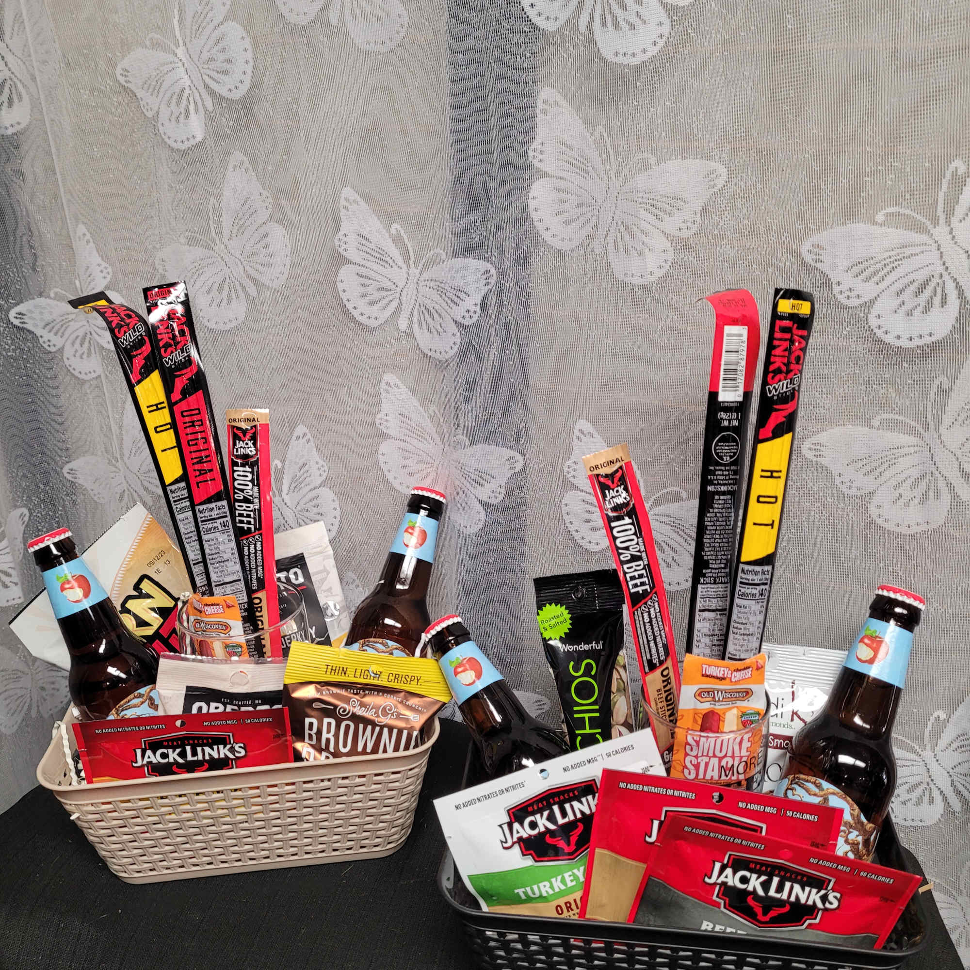 Two gift baskets filled with snacks and bottled drinks on a table