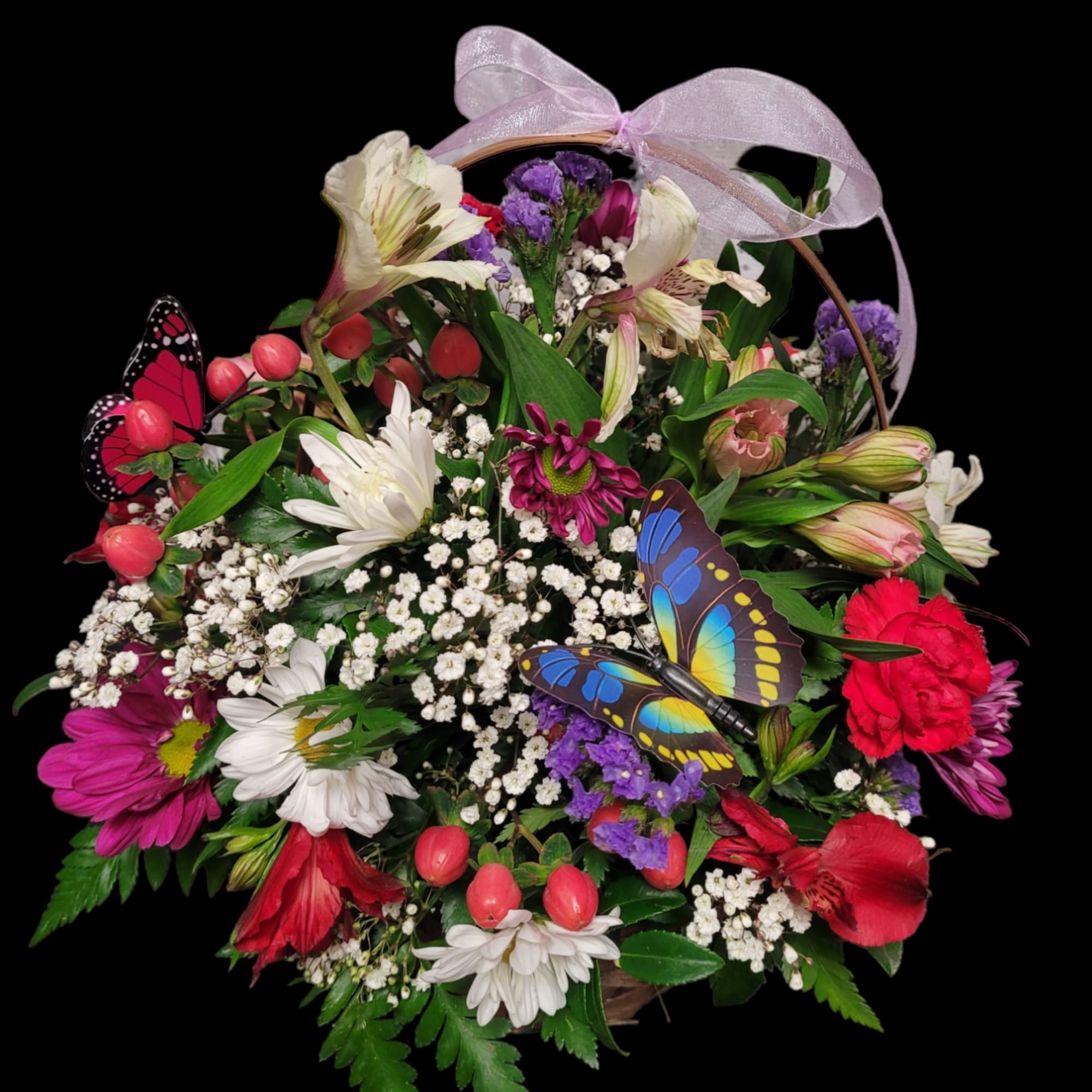 Basket arrangement of mixed flowers with butterfly decorations and a lavender ribbon