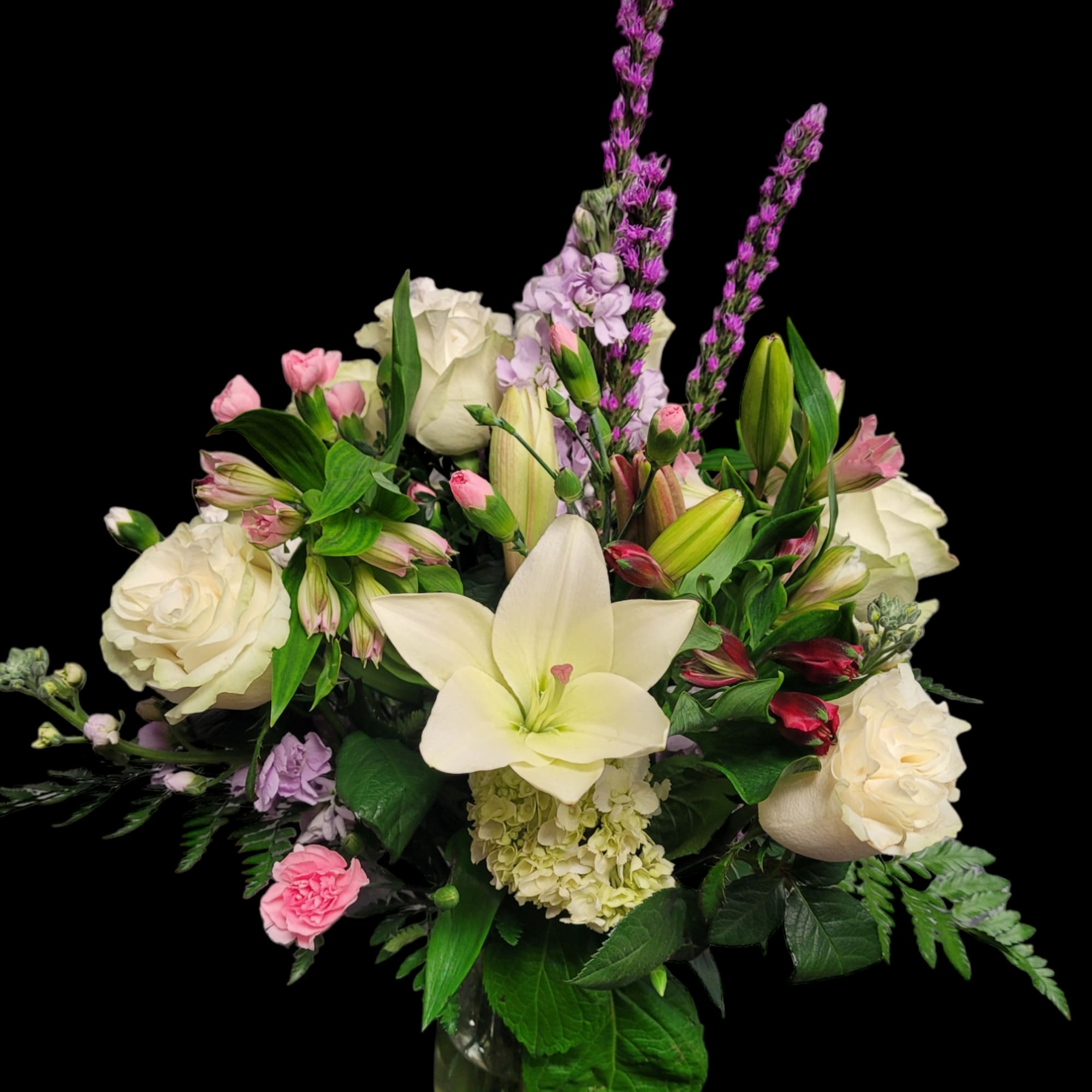 Bouquet of white roses, lilies, and pink flowers in a glass vase