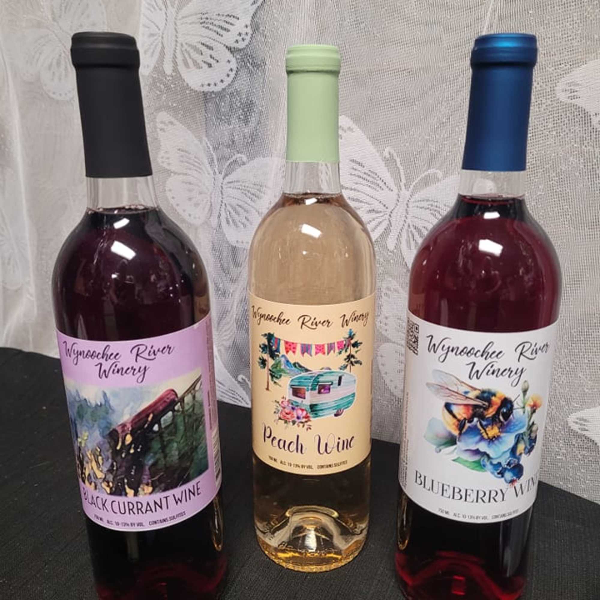 Three labeled wine bottles standing on a dark surface