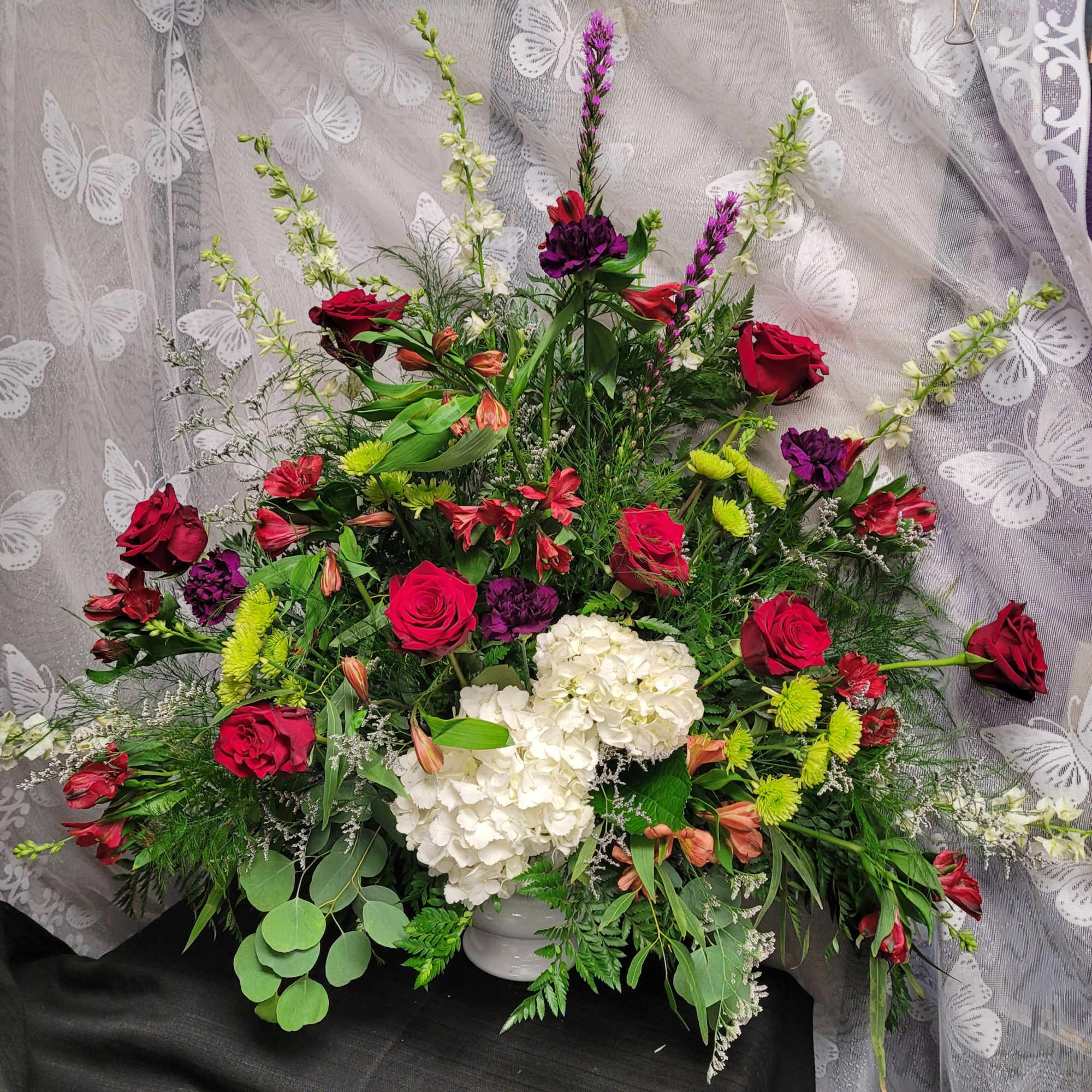 Large mixed bouquet with red roses, white hydrangeas, and purple flowers in a vase