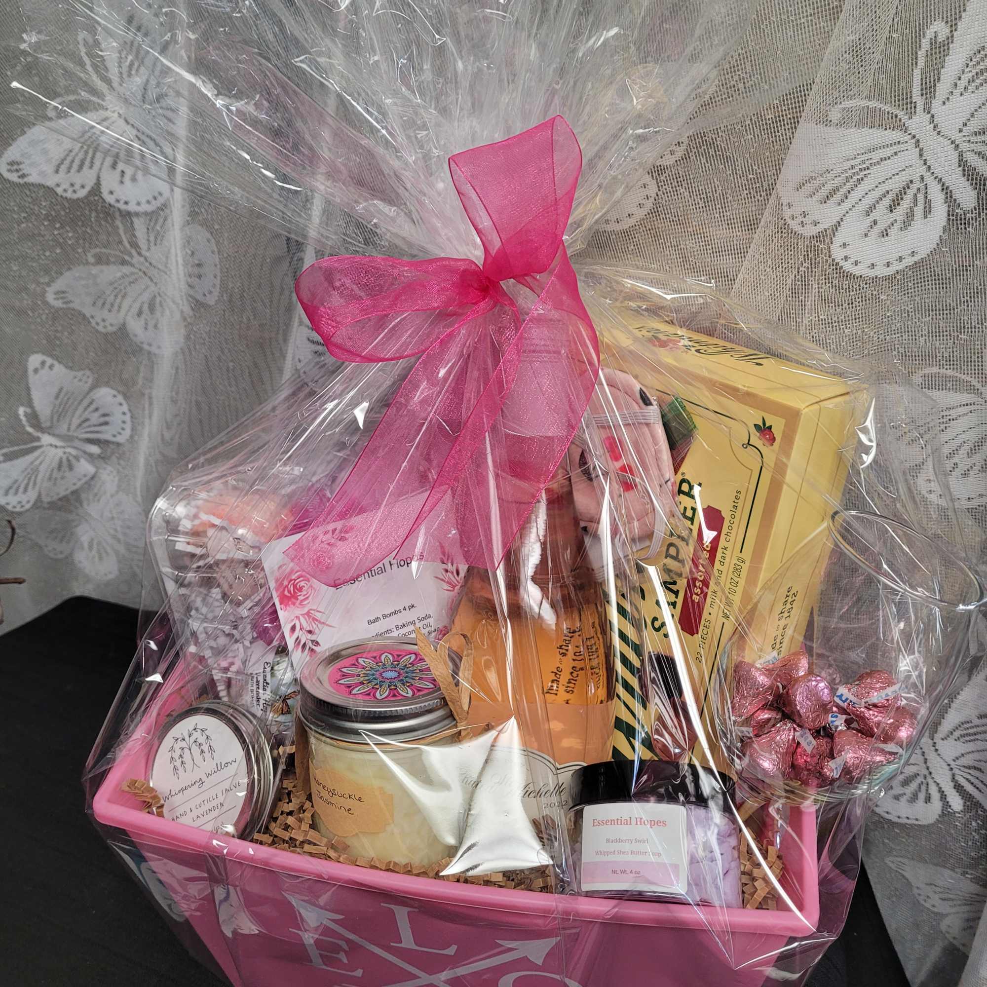 Gift basket with candles, chocolates, and bath items tied with a pink ribbon