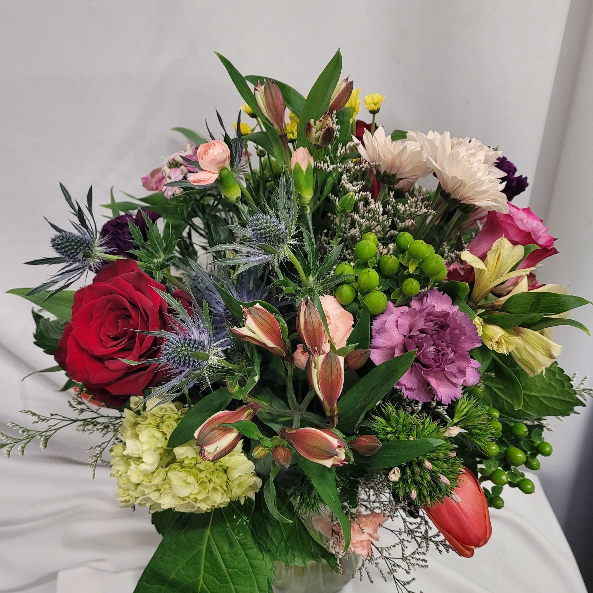 Mixed bouquet of roses, carnations, and lilies in a glass vase