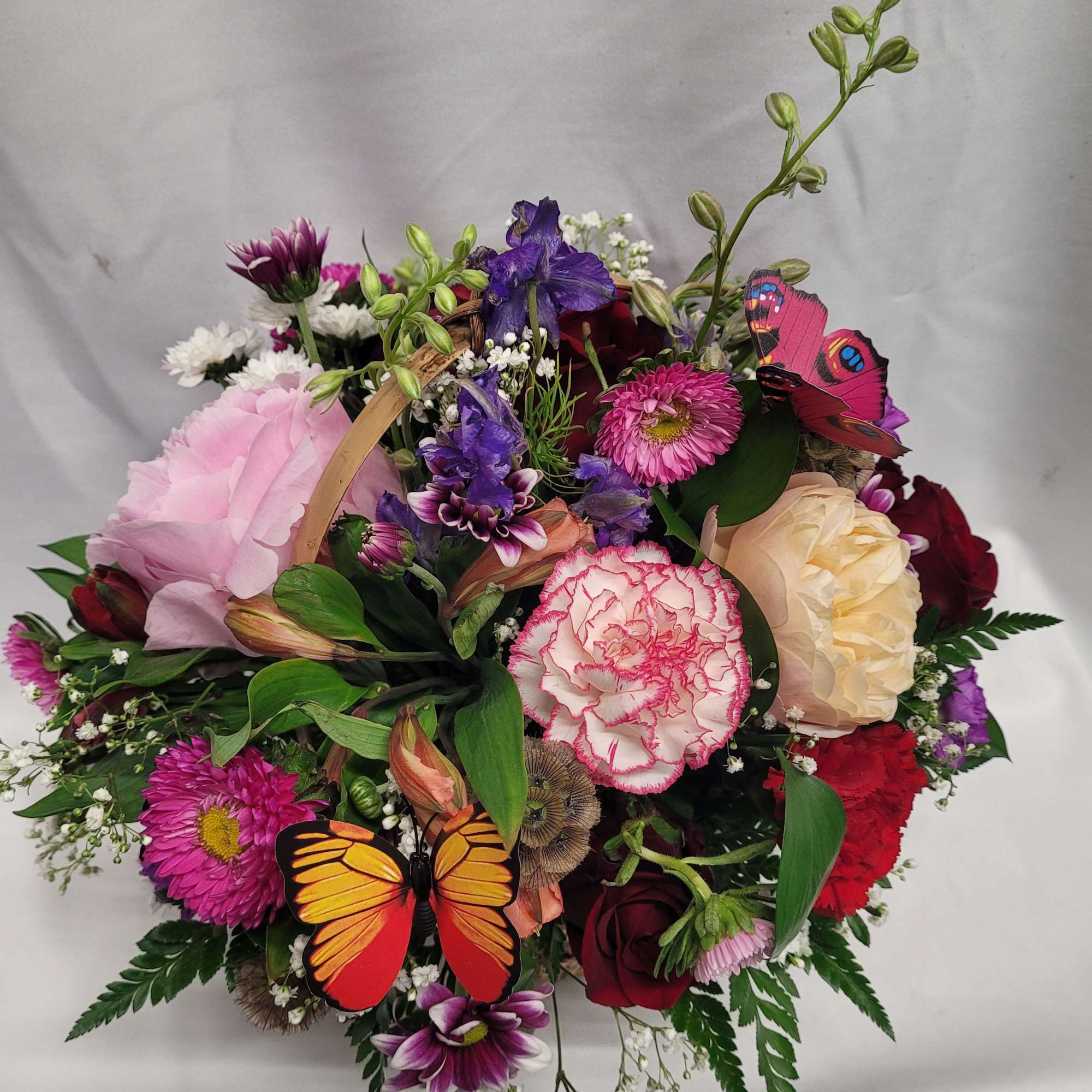 Mixed bouquet with pink, purple, red, and cream flowers and butterfly decorations