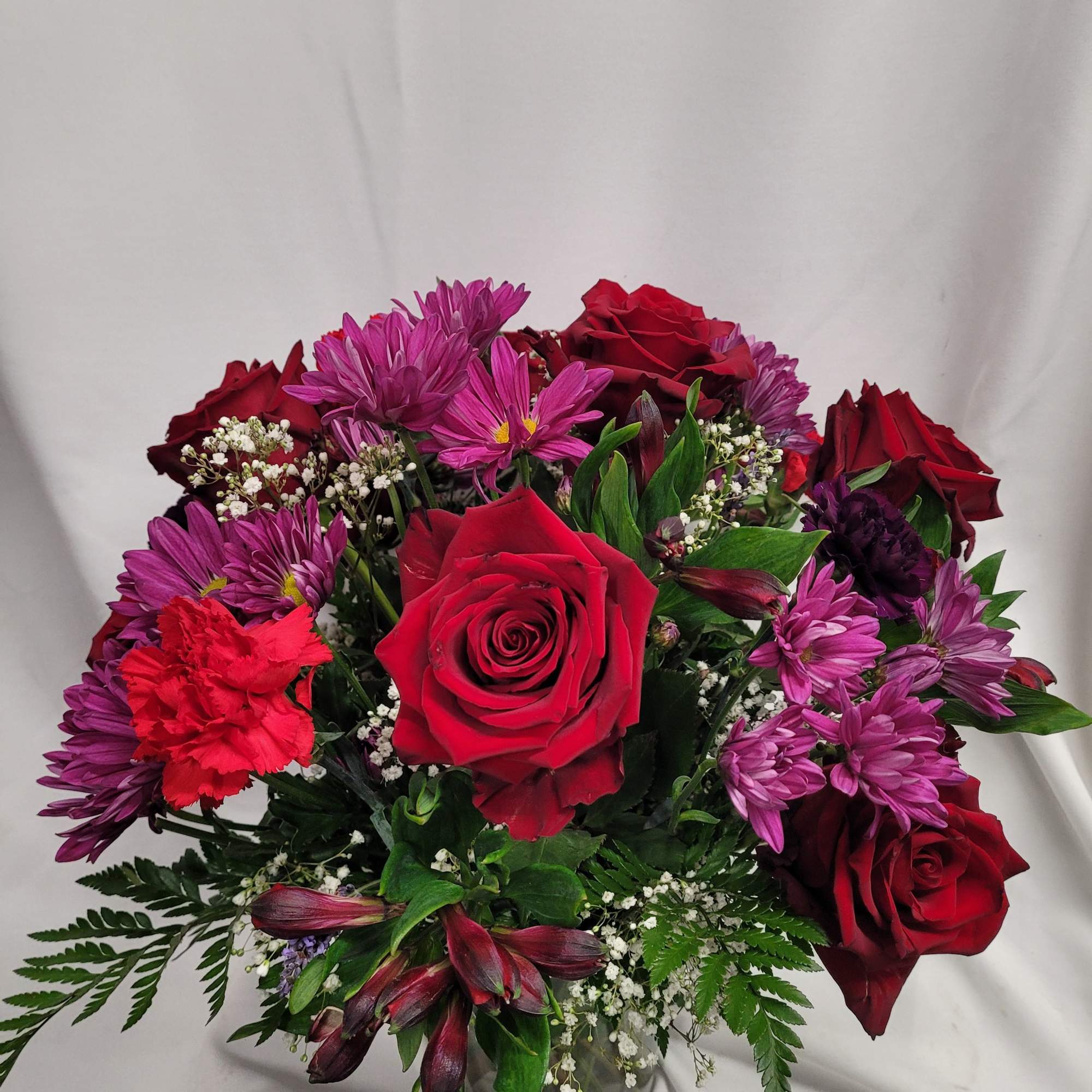 Bouquet of red roses and purple daisies in a glass vase