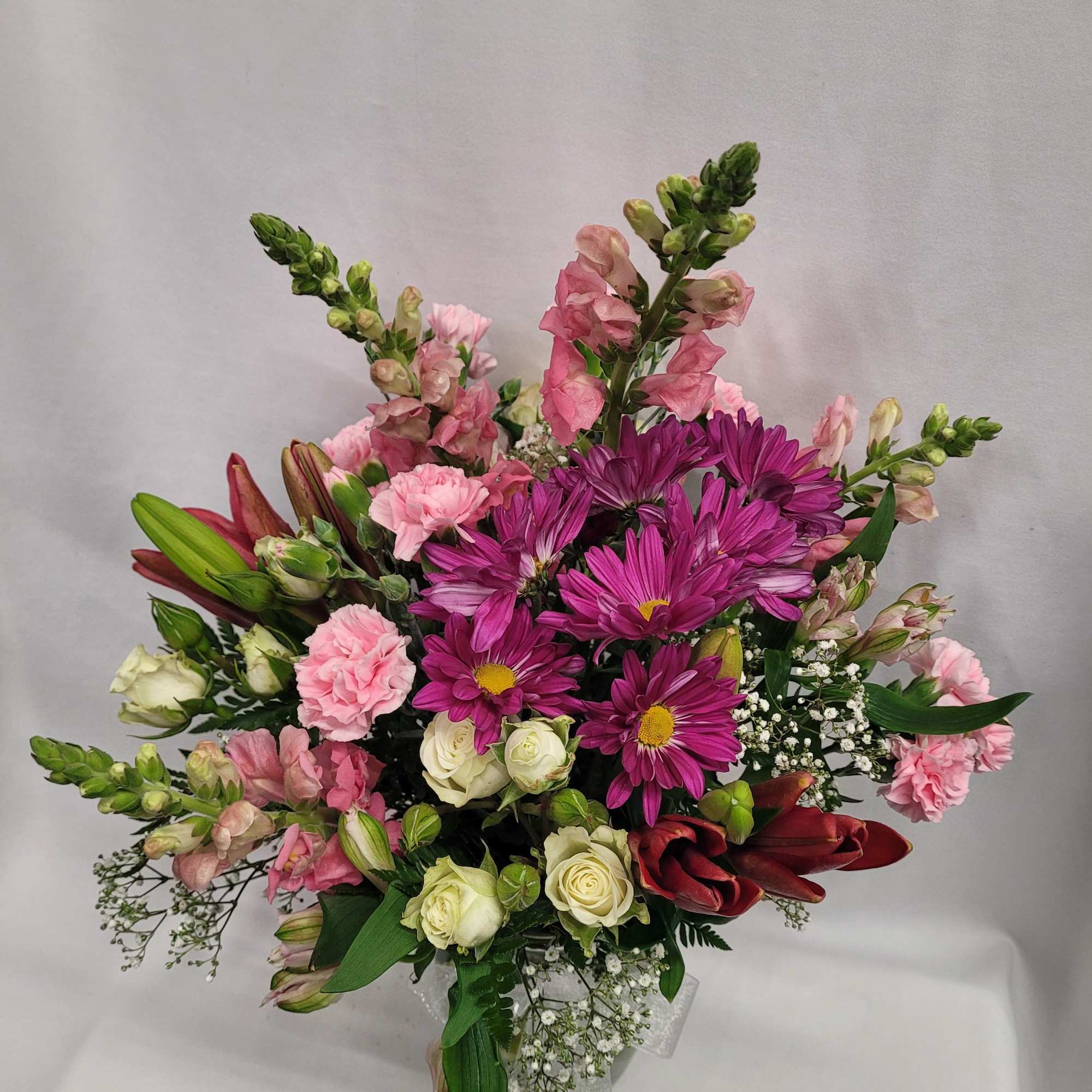 Bouquet of pink and purple flowers with white roses in a clear vase