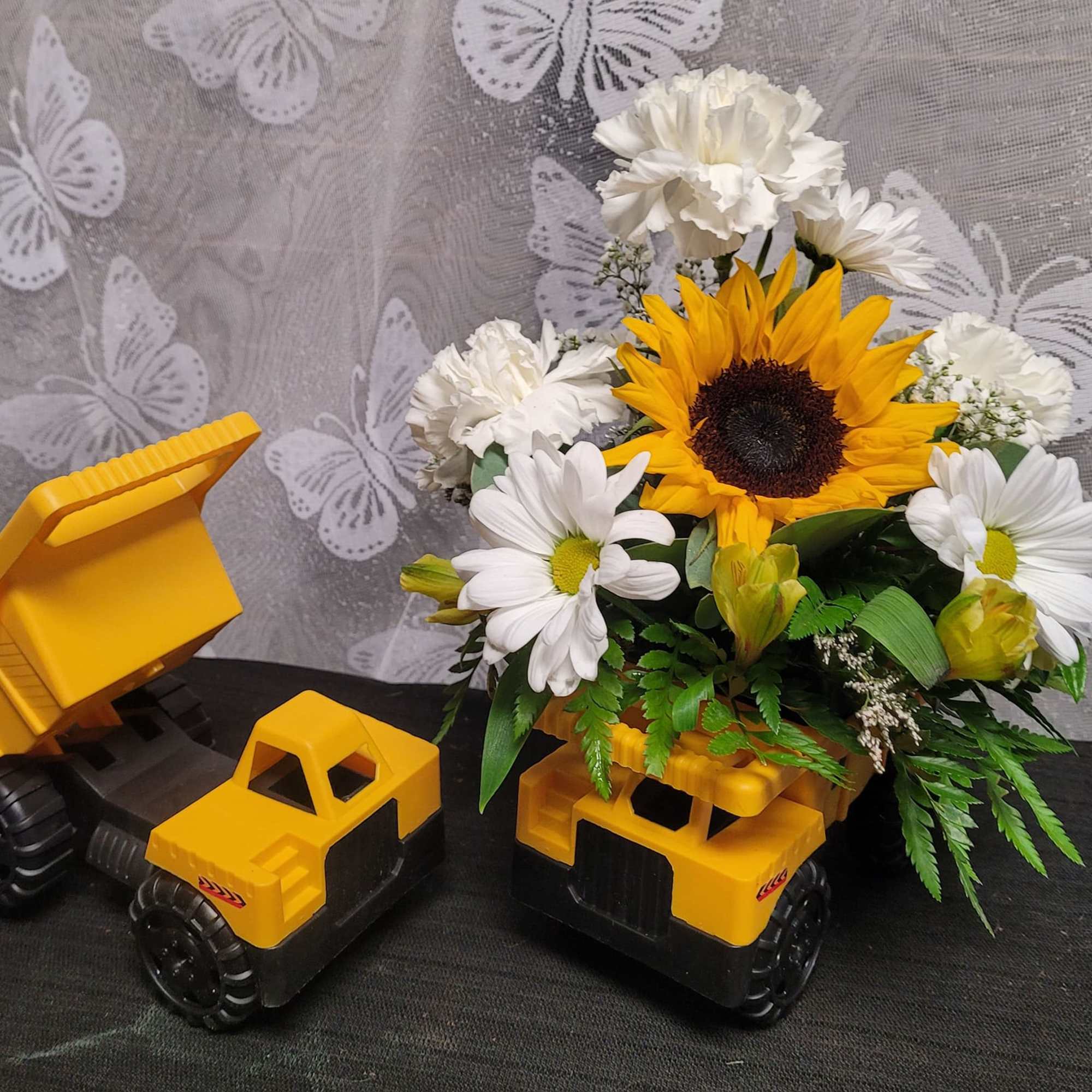Sunflower and white daisy arrangement in a yellow toy dump truck