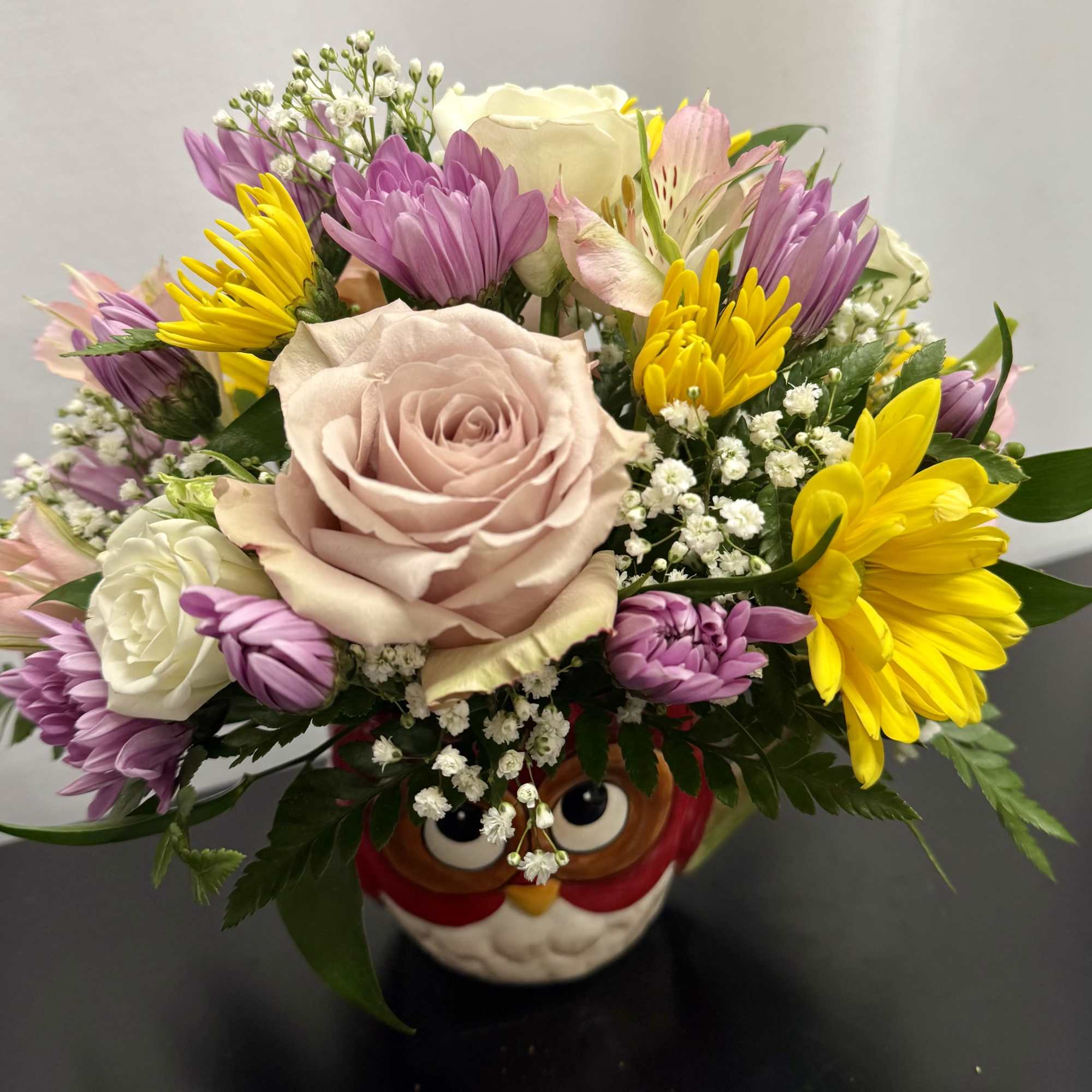 Mixed bouquet with a pale pink rose in an owl-shaped vase
