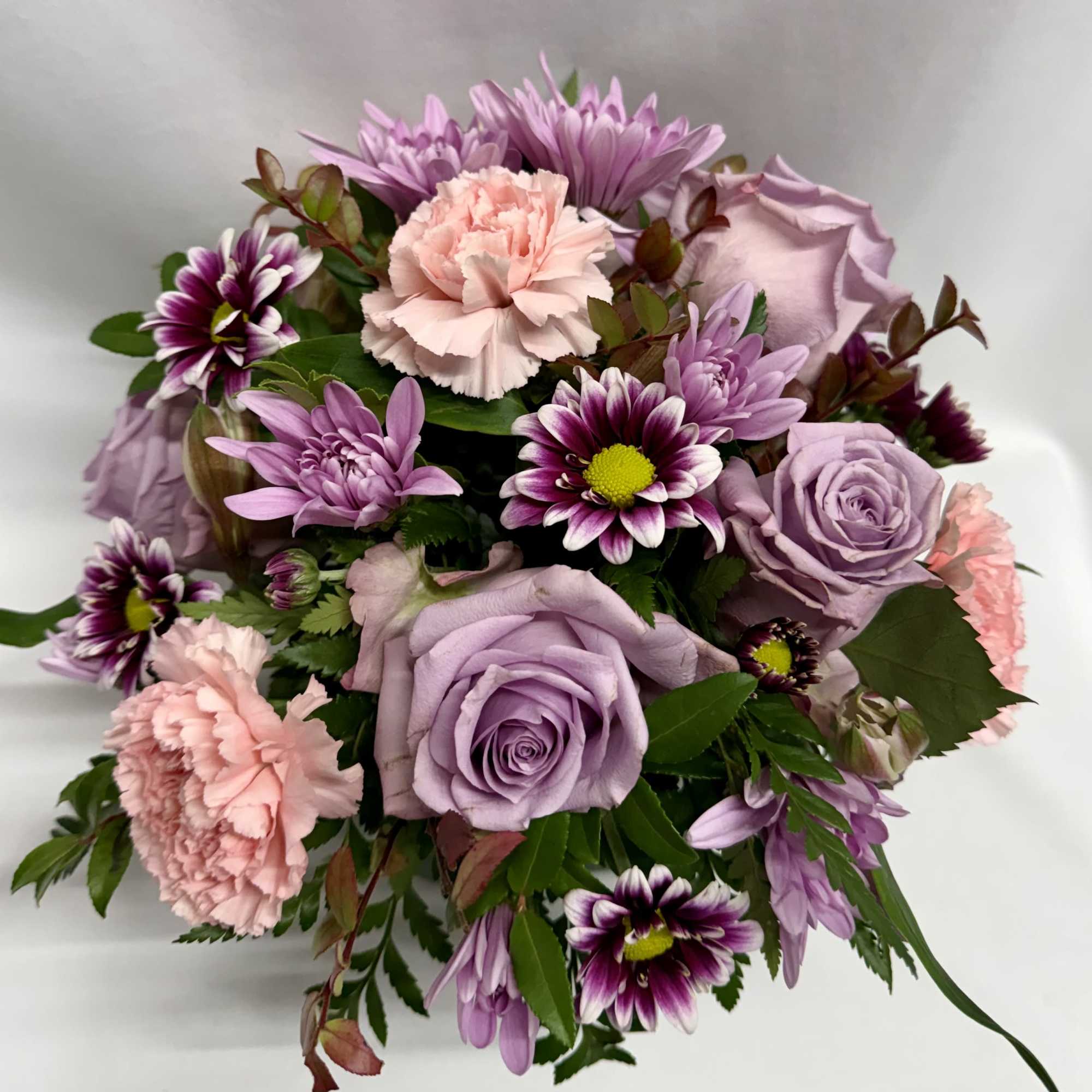 Lavender roses and pink carnations with purple daisies in a bouquet