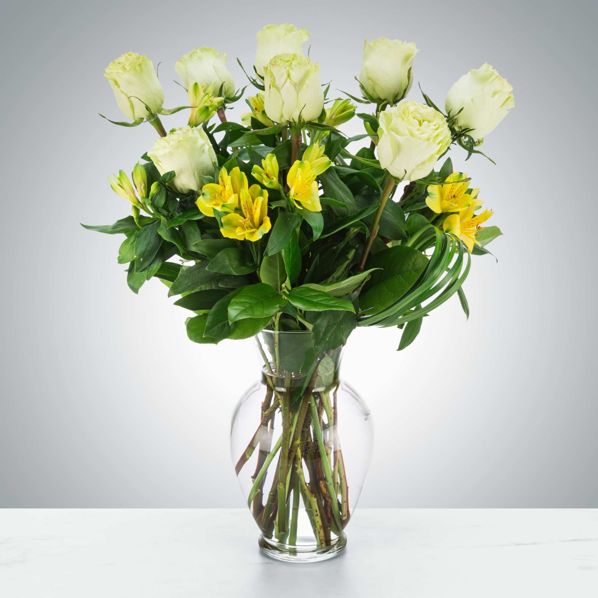 White roses and yellow alstroemeria in a clear glass vase