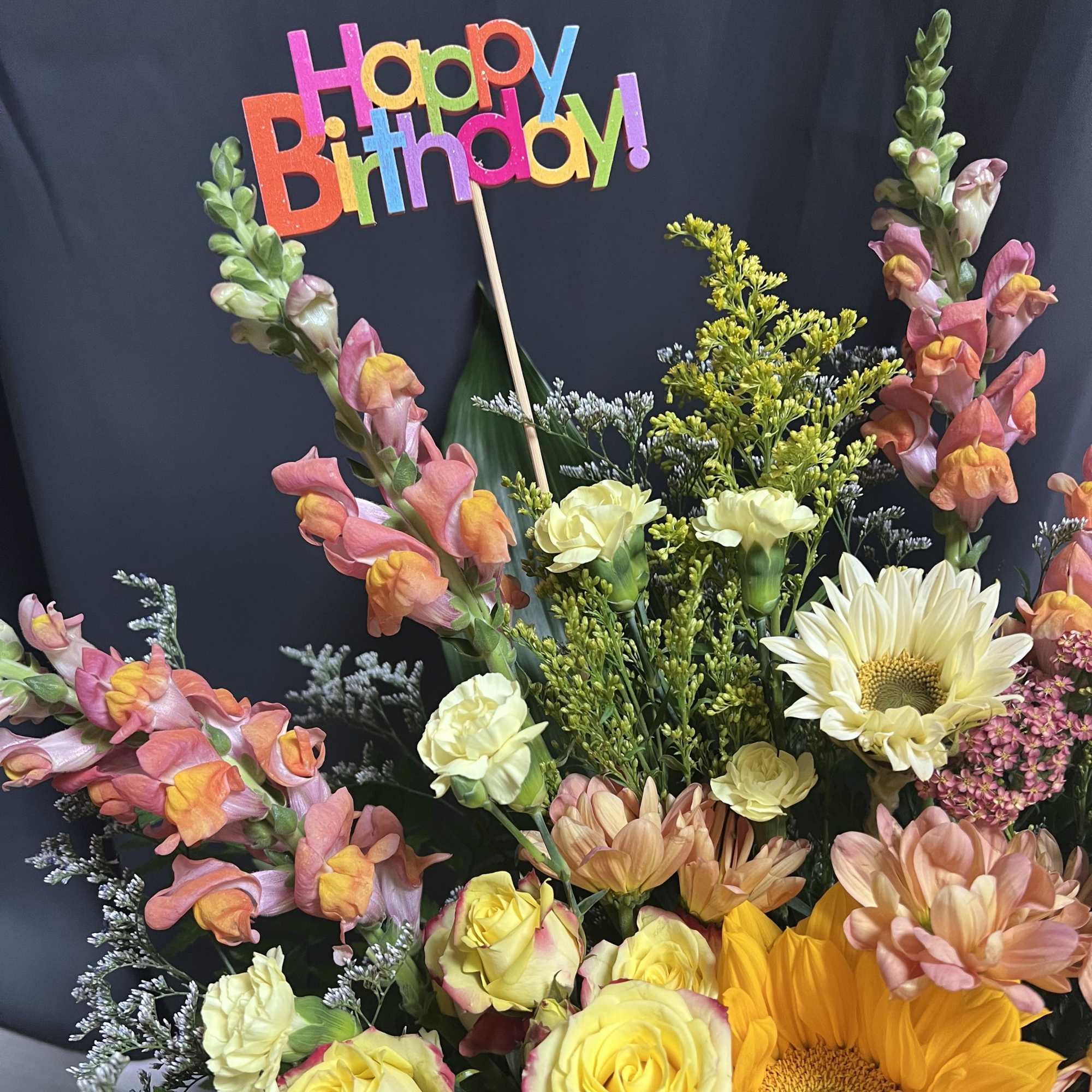 Mixed bouquet with sunflowers, roses, snapdragons, and a Happy Birthday sign