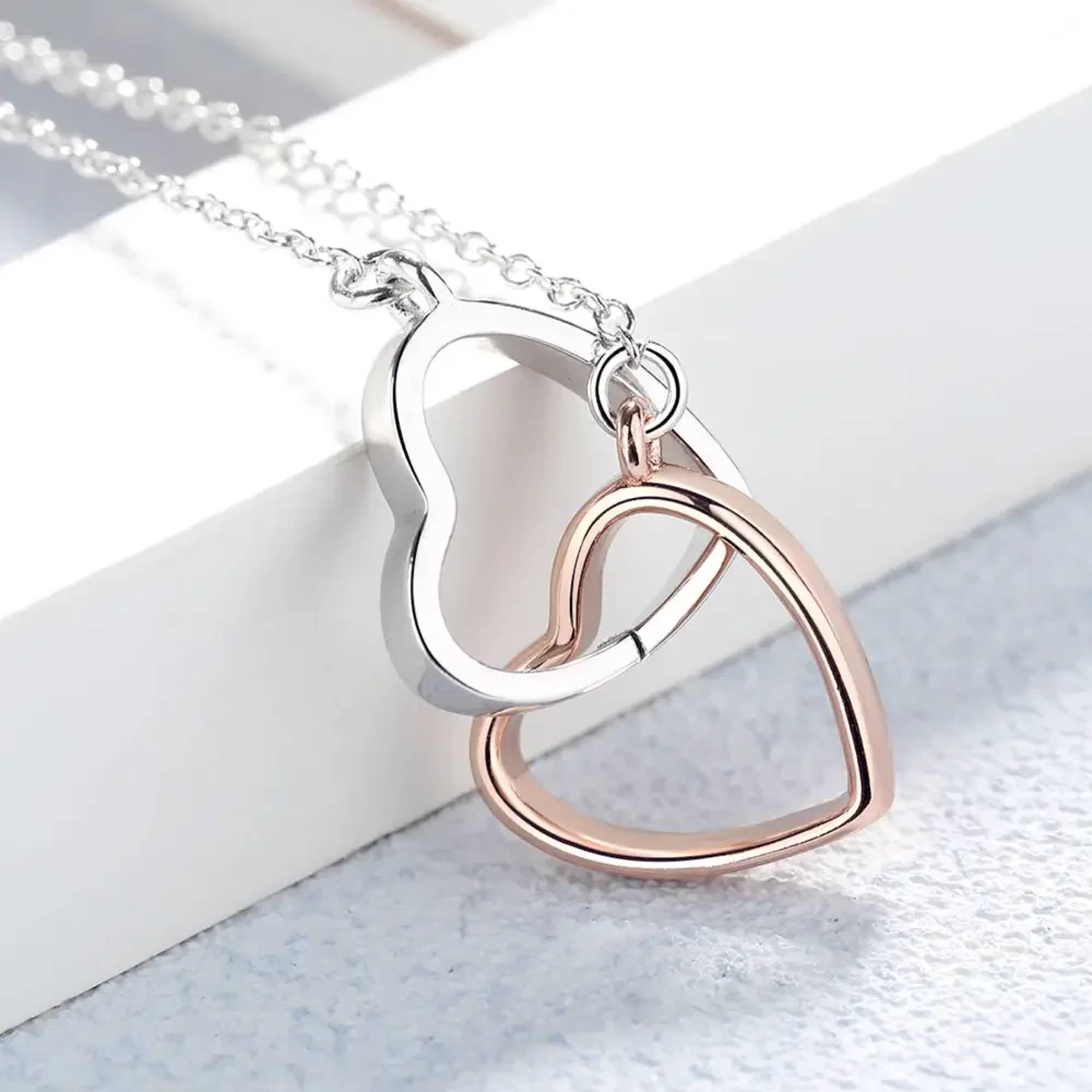 Two interlocking heart pendants on a silver chain