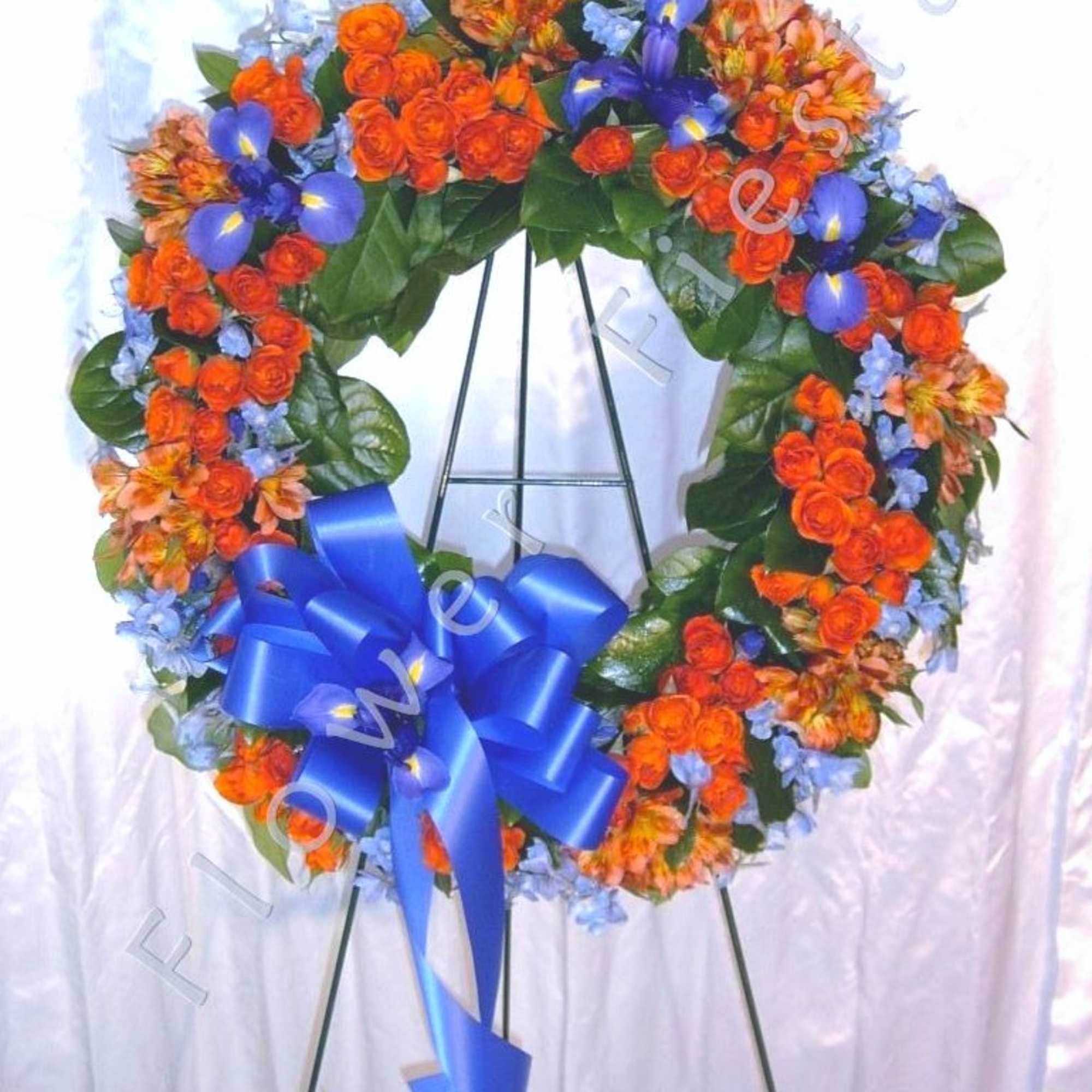 Heart-shaped floral wreath with orange and blue flowers on an easel