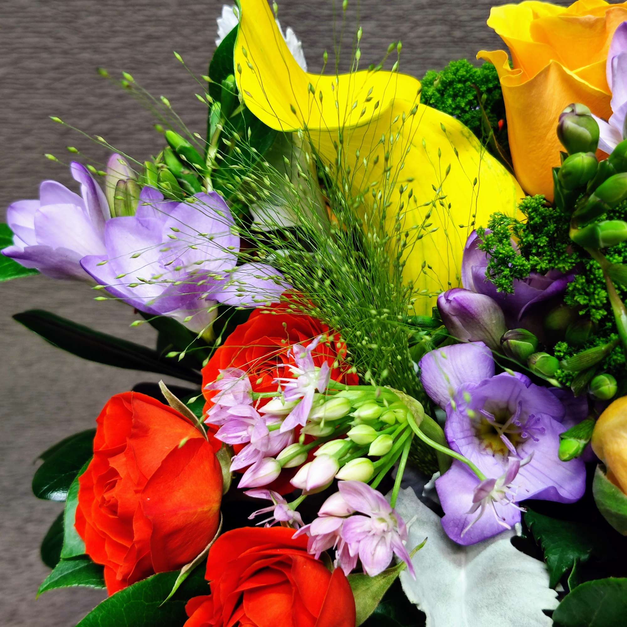 Bouquet of red, yellow, and purple flowers with green filler