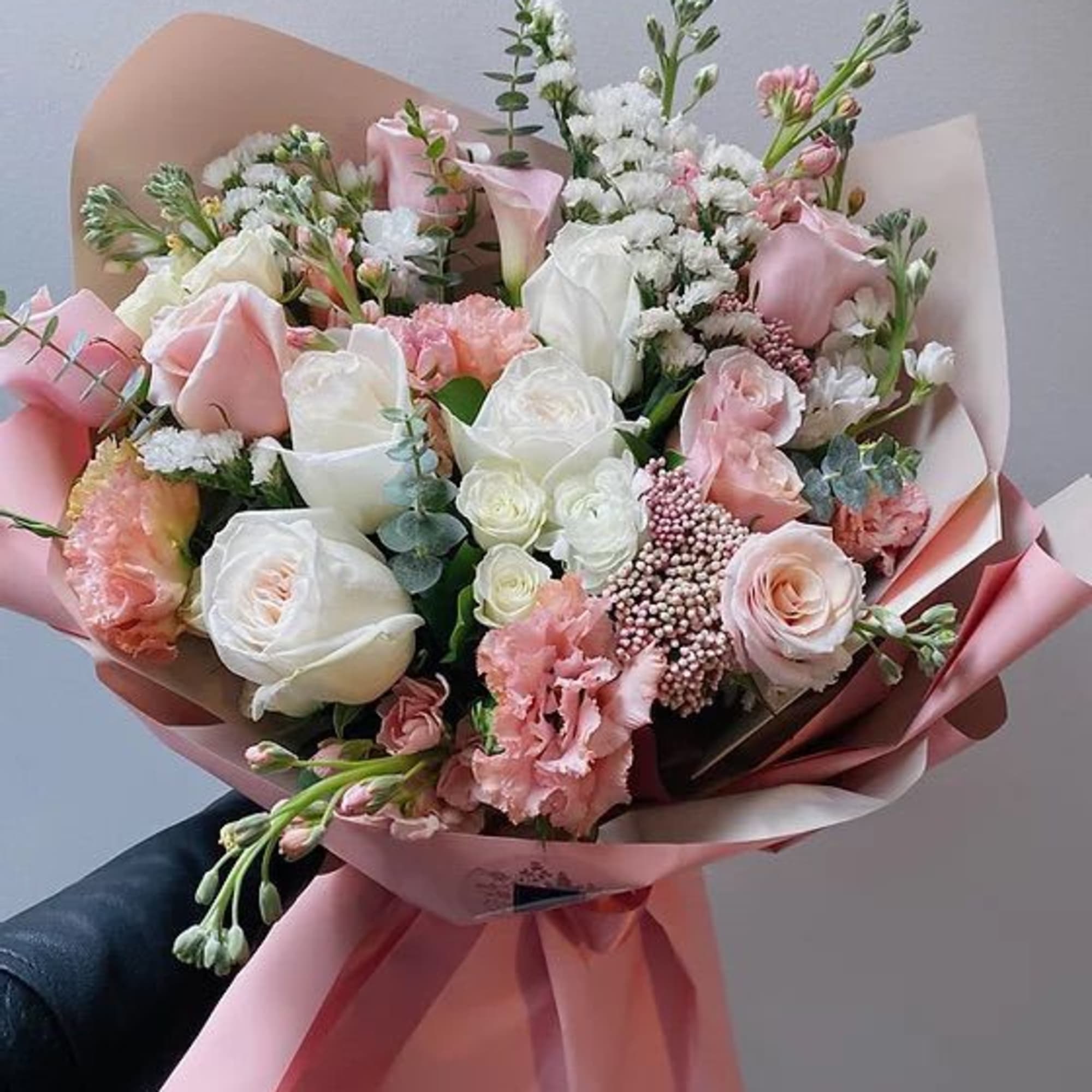 Hand-tied bouquet of pink and white roses with pink wrapping