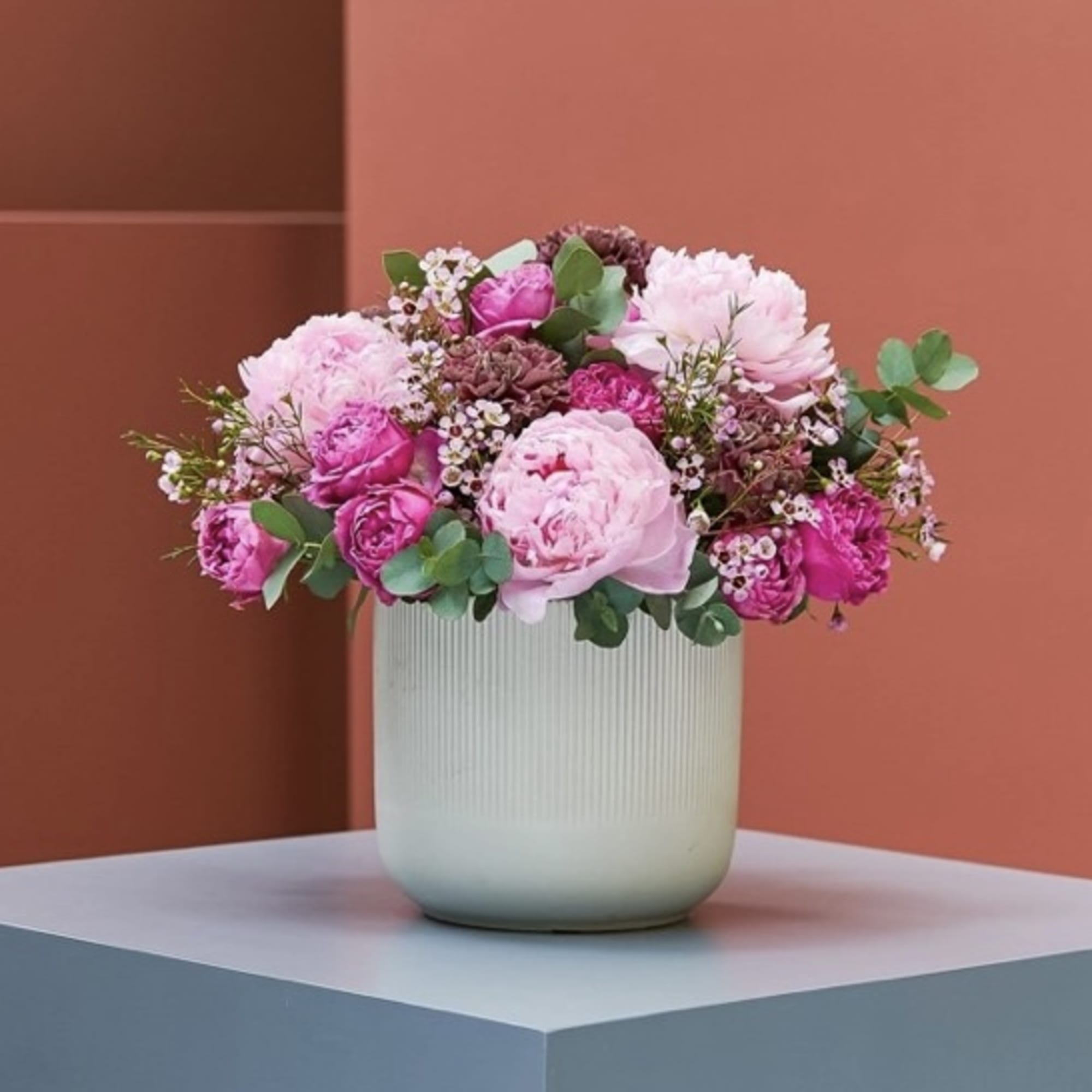 Pink floral arrangement in a ribbed white vase