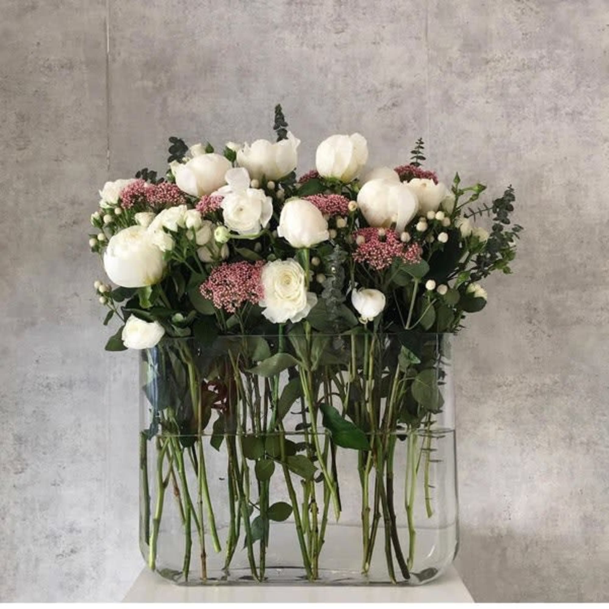 White roses and pink filler flowers in a clear glass vase