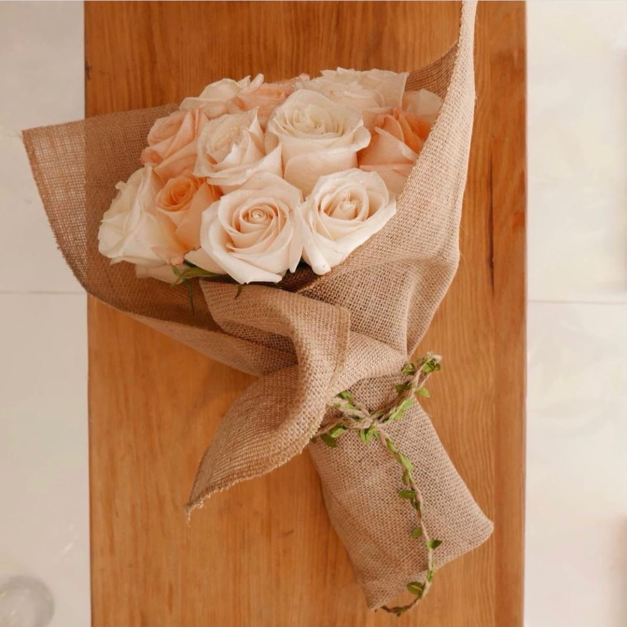 Bouquet of pale peach roses wrapped in burlap