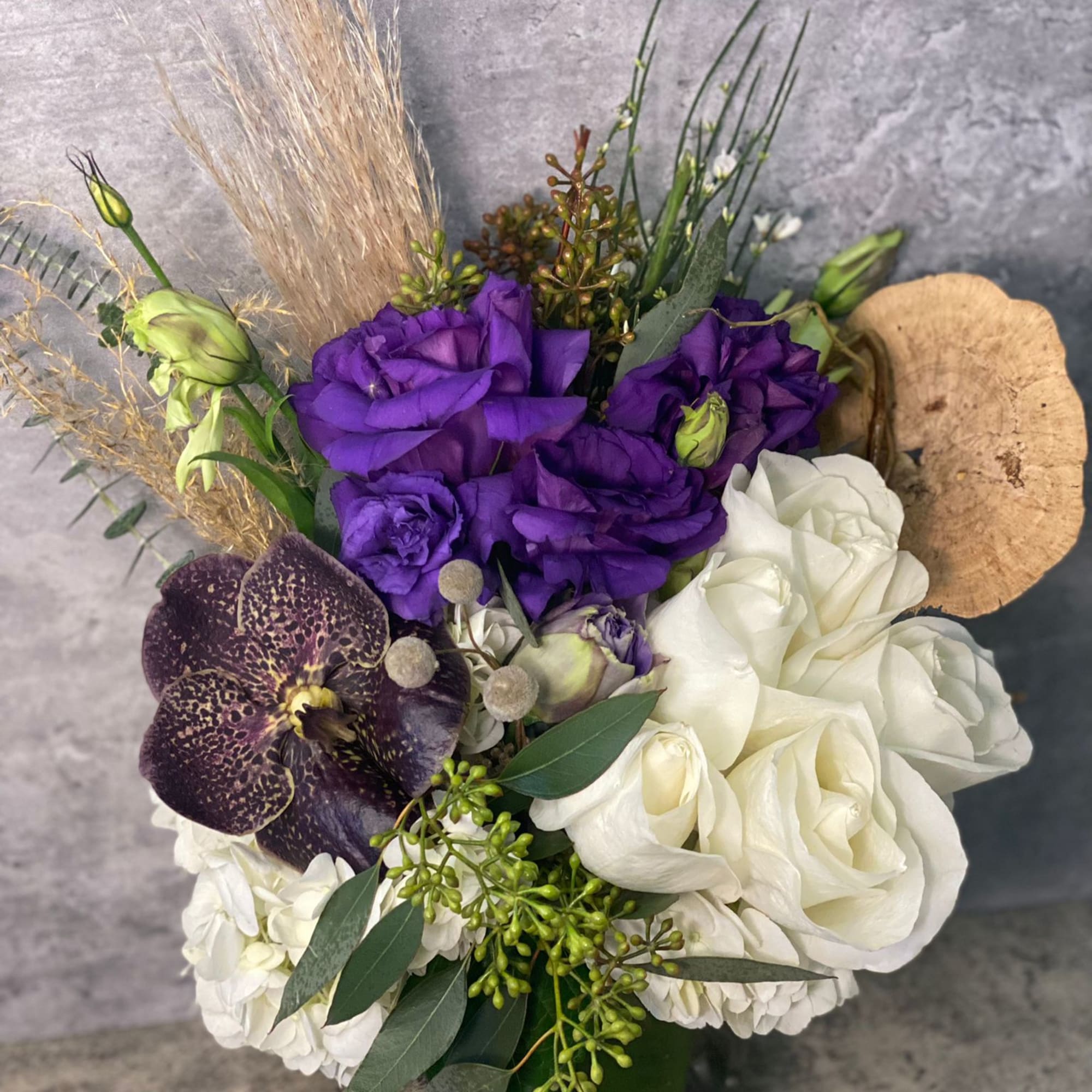 Purple and white floral arrangement with orchids in a vase